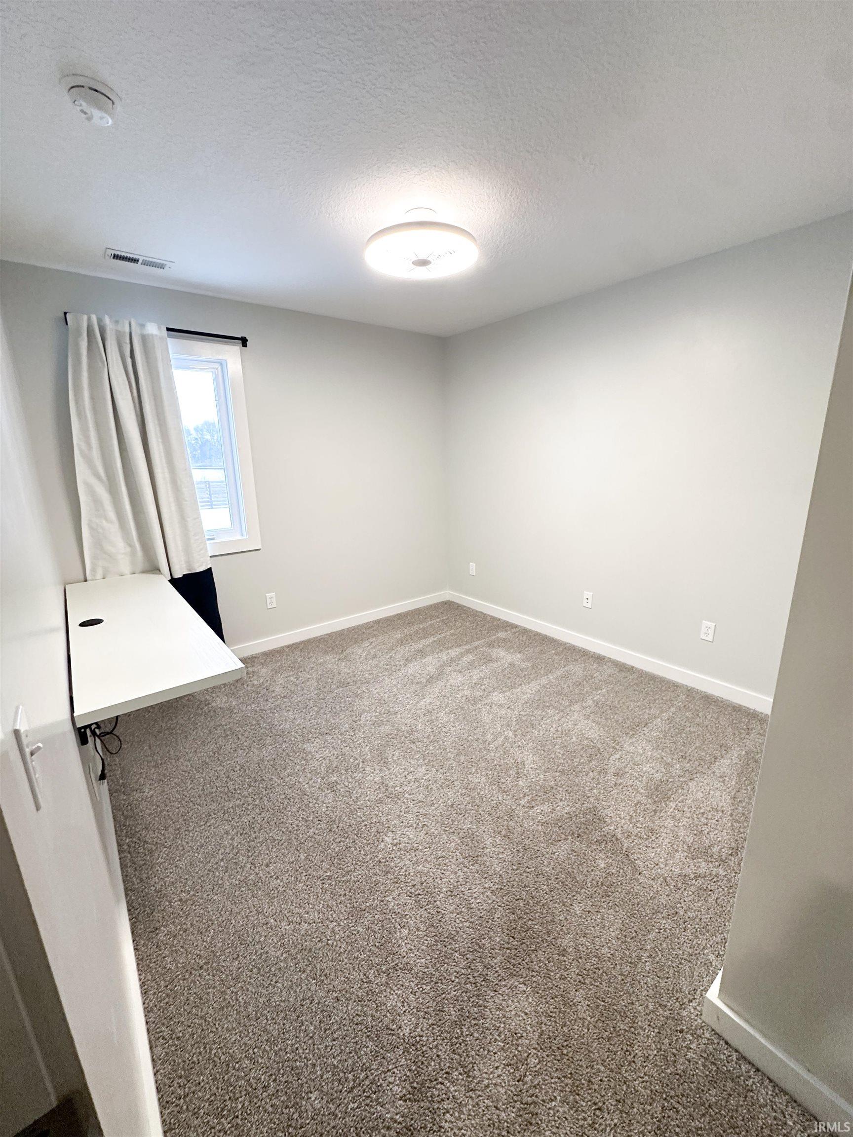 Bedroom with a textured ceiling and light colored carpet