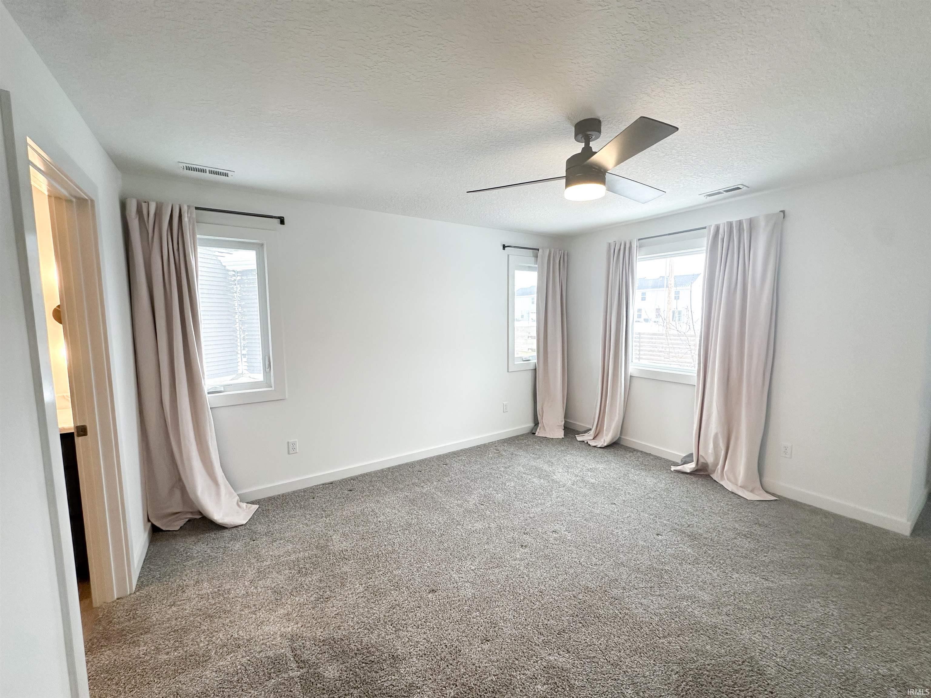 Unfurnished bedroom with carpet floors, a textured ceiling, and a ceiling fan