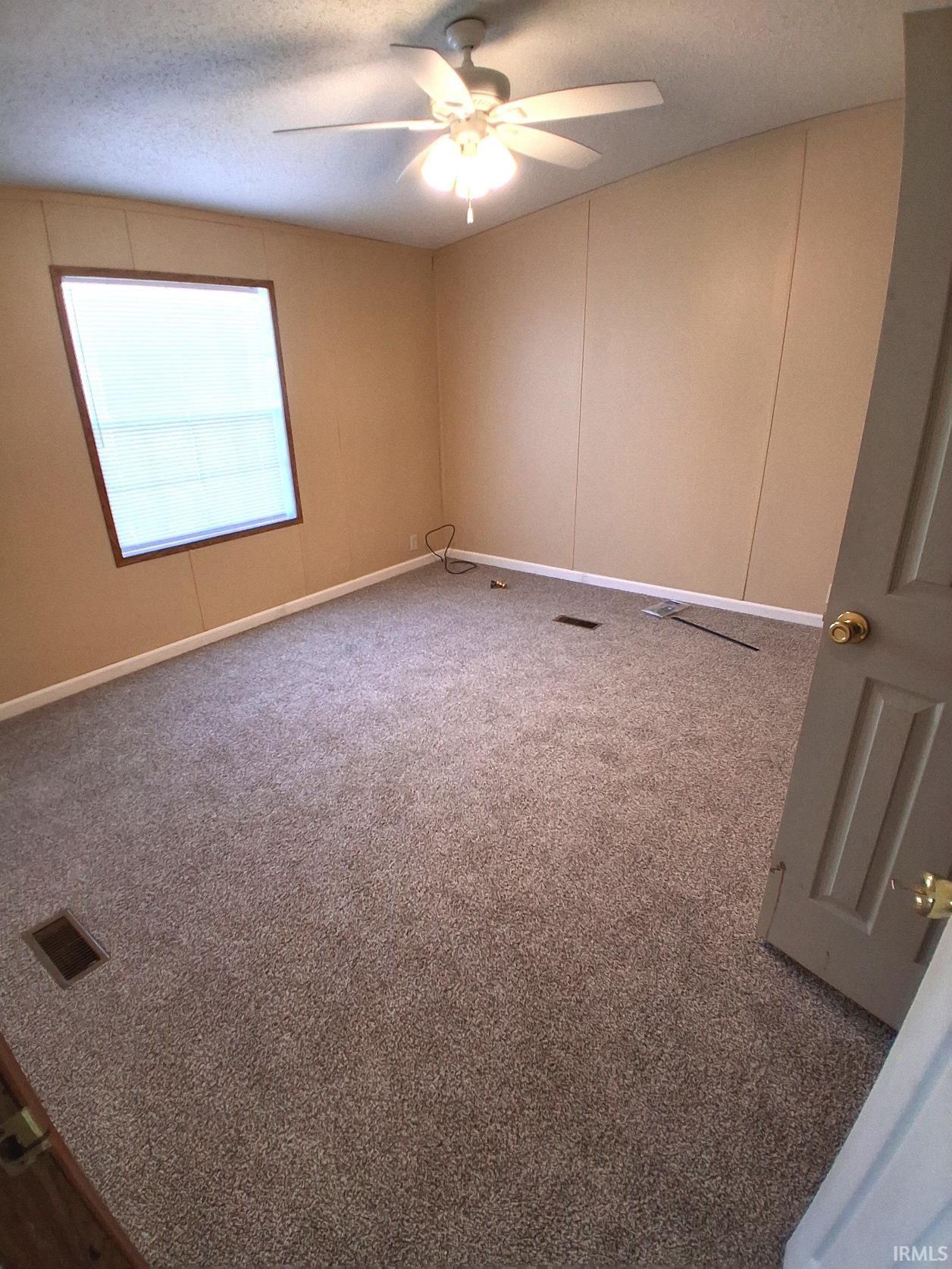 Carpeted bedroom with a textured ceiling, new ceiling fan and walk in closet