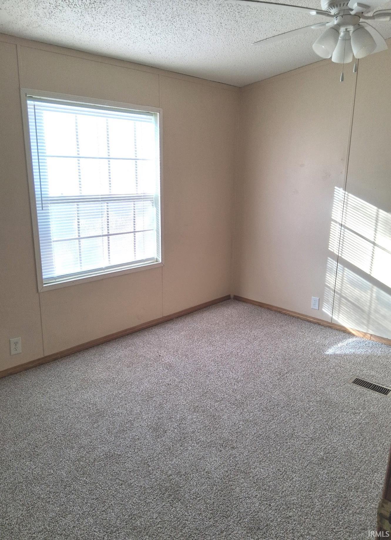 bedroom featuring carpet, new ceiling fan, and a textured ceiling