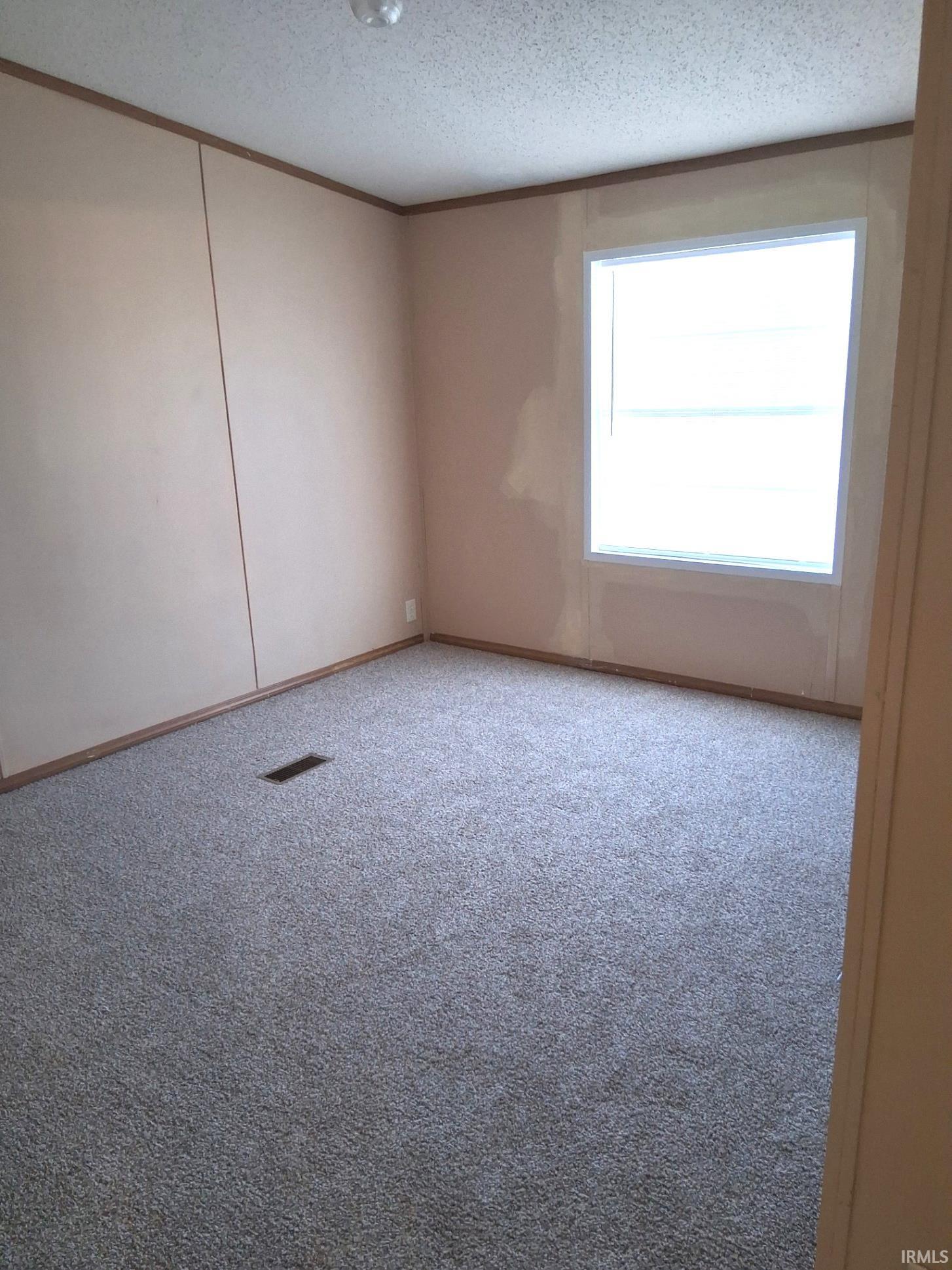 Bedroom with a textured ceiling, light colored carpet, and new ceiling fan