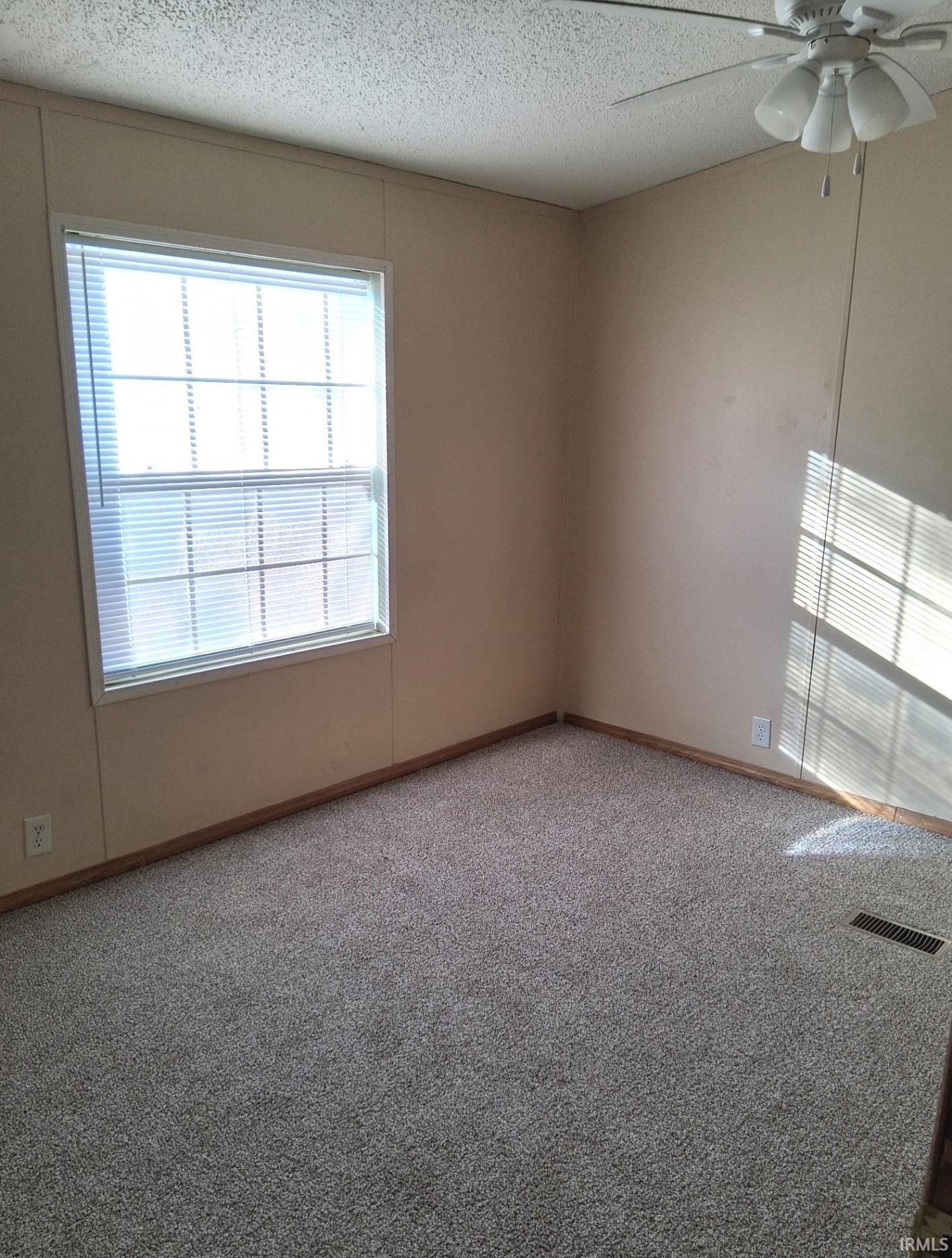 Carpeted master bedroom featuring new ceiling fan and a textured ceiling. Walk in closet