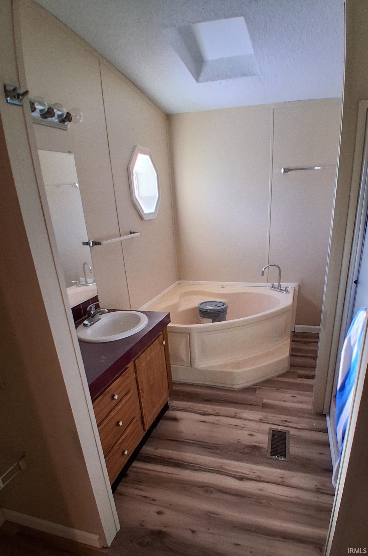 Full bathroom featuring a garden tub, vanity, new vinyl plank floor, a shower and a textured ceiling