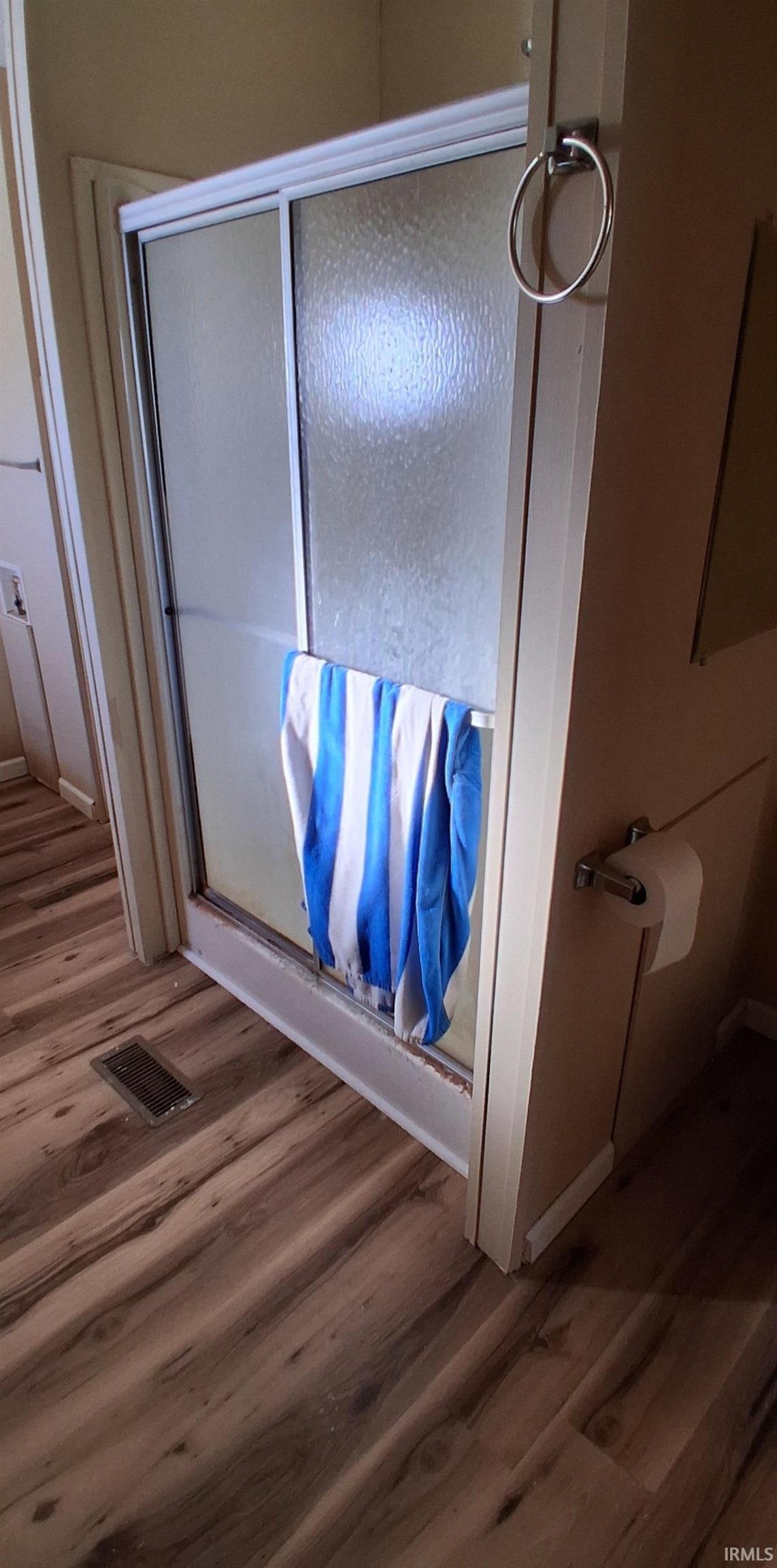 Bathroom featuring new vinyl plank floors and a stall shower