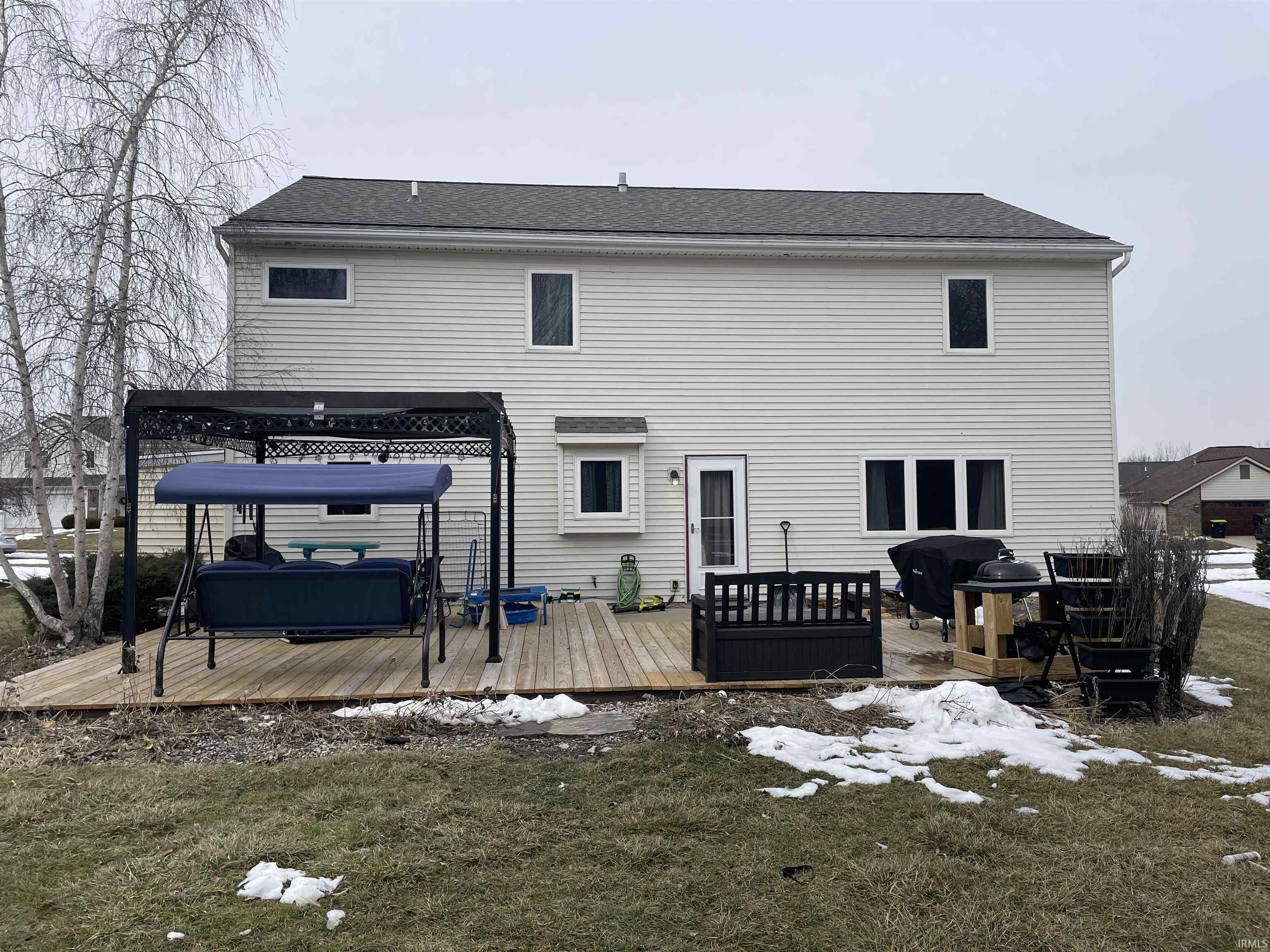 Back of house featuring a deck, a jacuzzi, a lawn, and a shingled roof