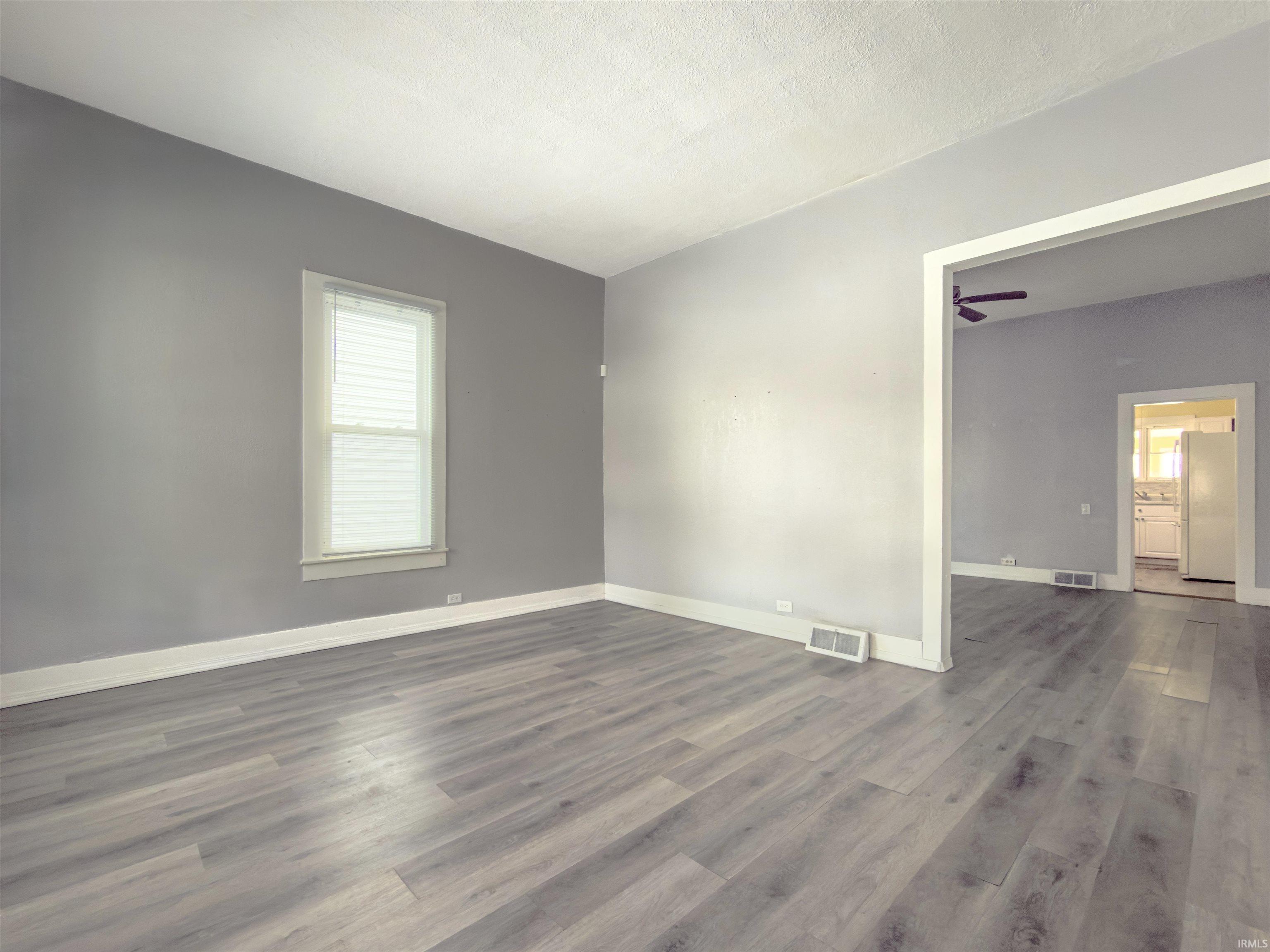 Empty room with dark wood-type flooring and a textured ceiling