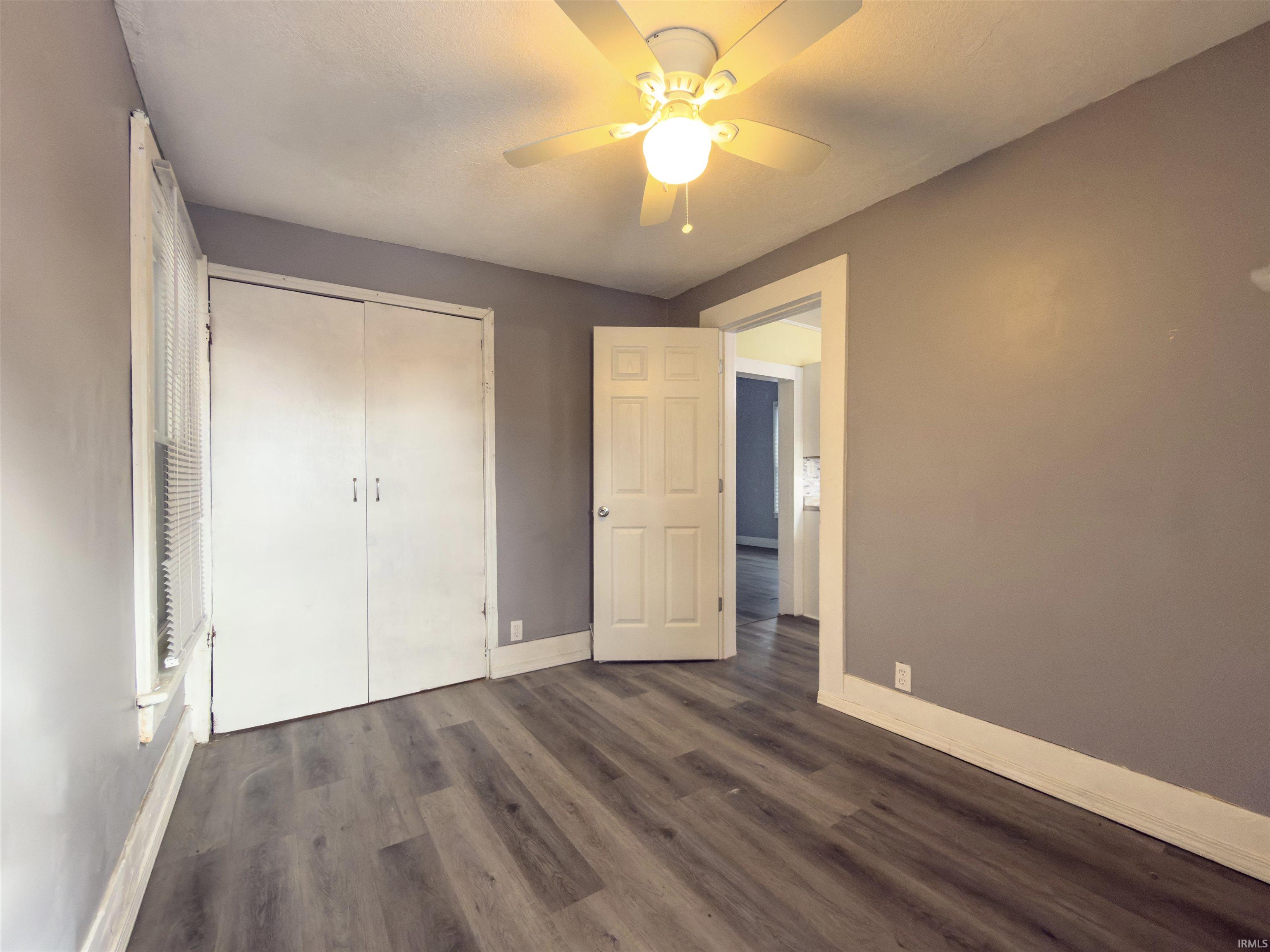 Unfurnished bedroom with dark wood-type flooring, a ceiling fan, and a closet