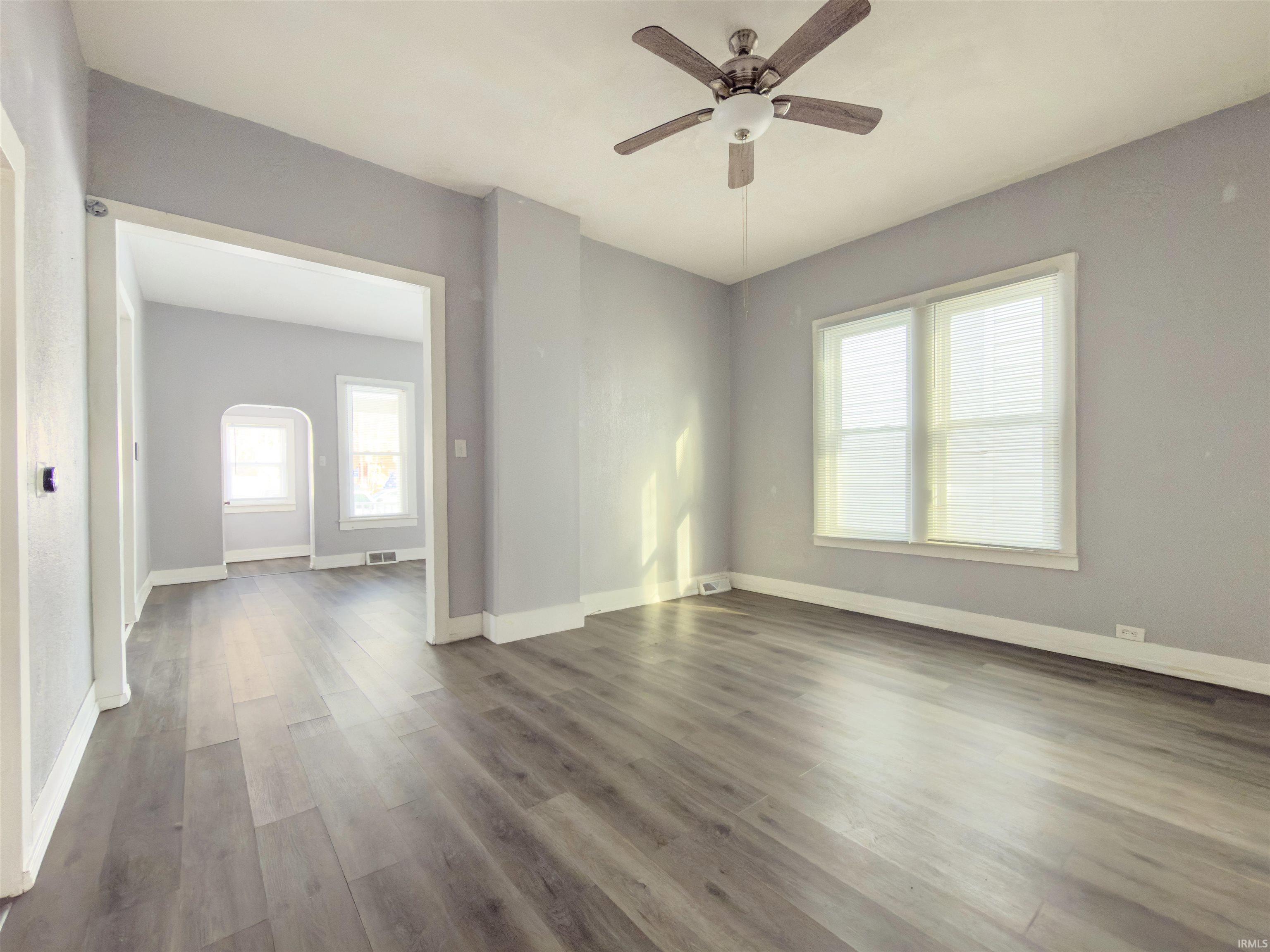 Empty room featuring dark wood-style flooring and ceiling fan