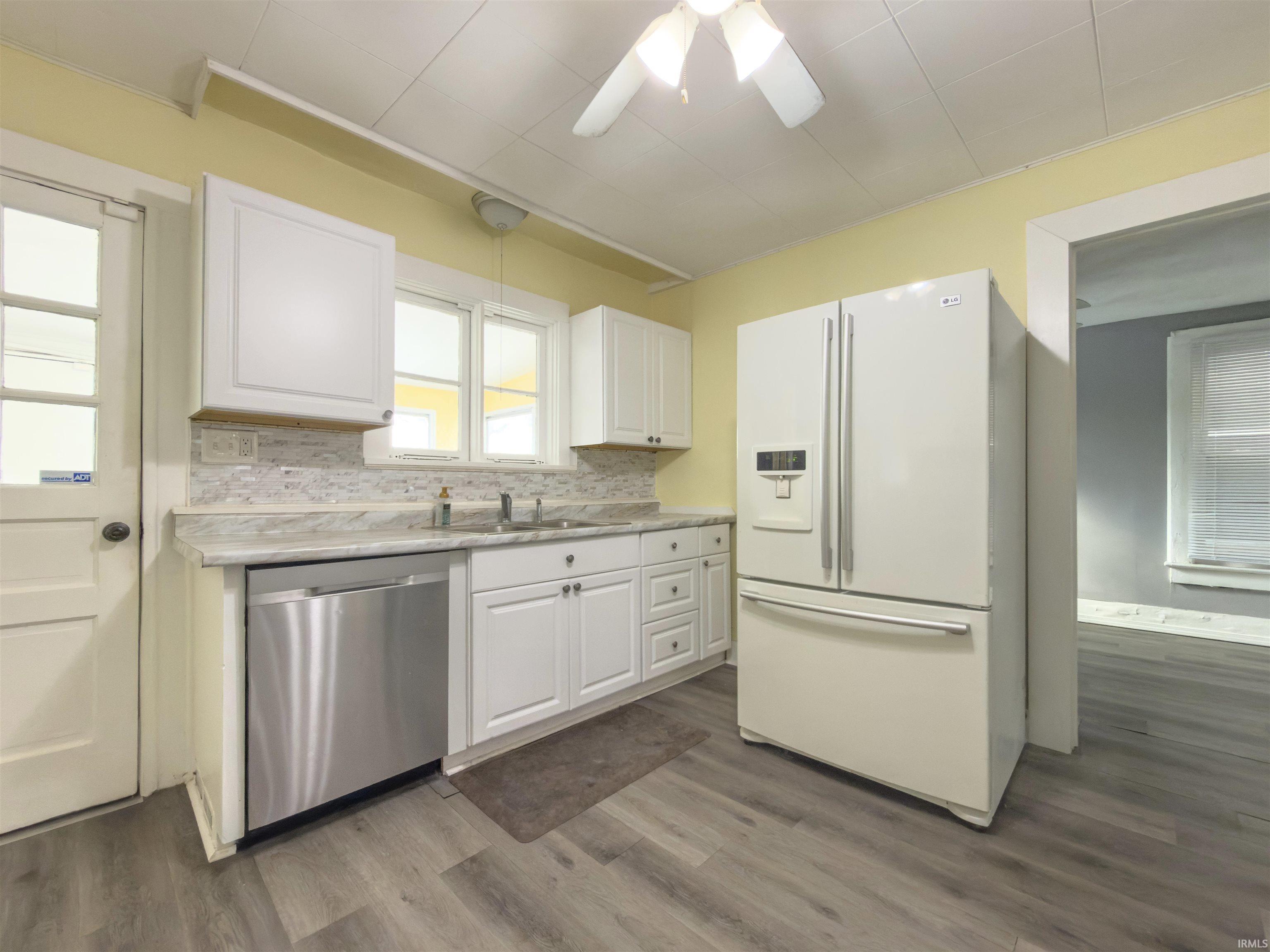 Kitchen with white fridge with ice dispenser, white cabinetry, a ceiling fan, and light countertops