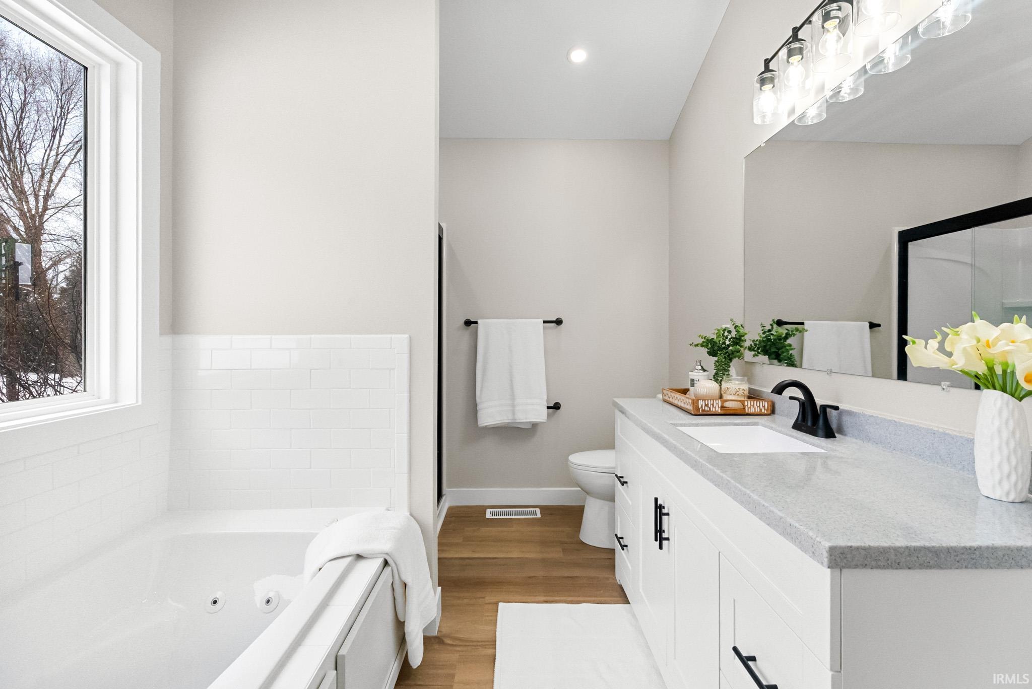 Full bath featuring vanity, a whirlpool tub, light wood-type flooring, and recessed lighting