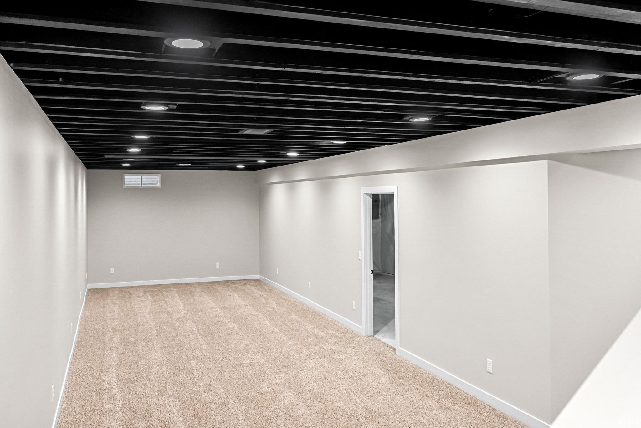 Basement with light colored carpet and baseboards