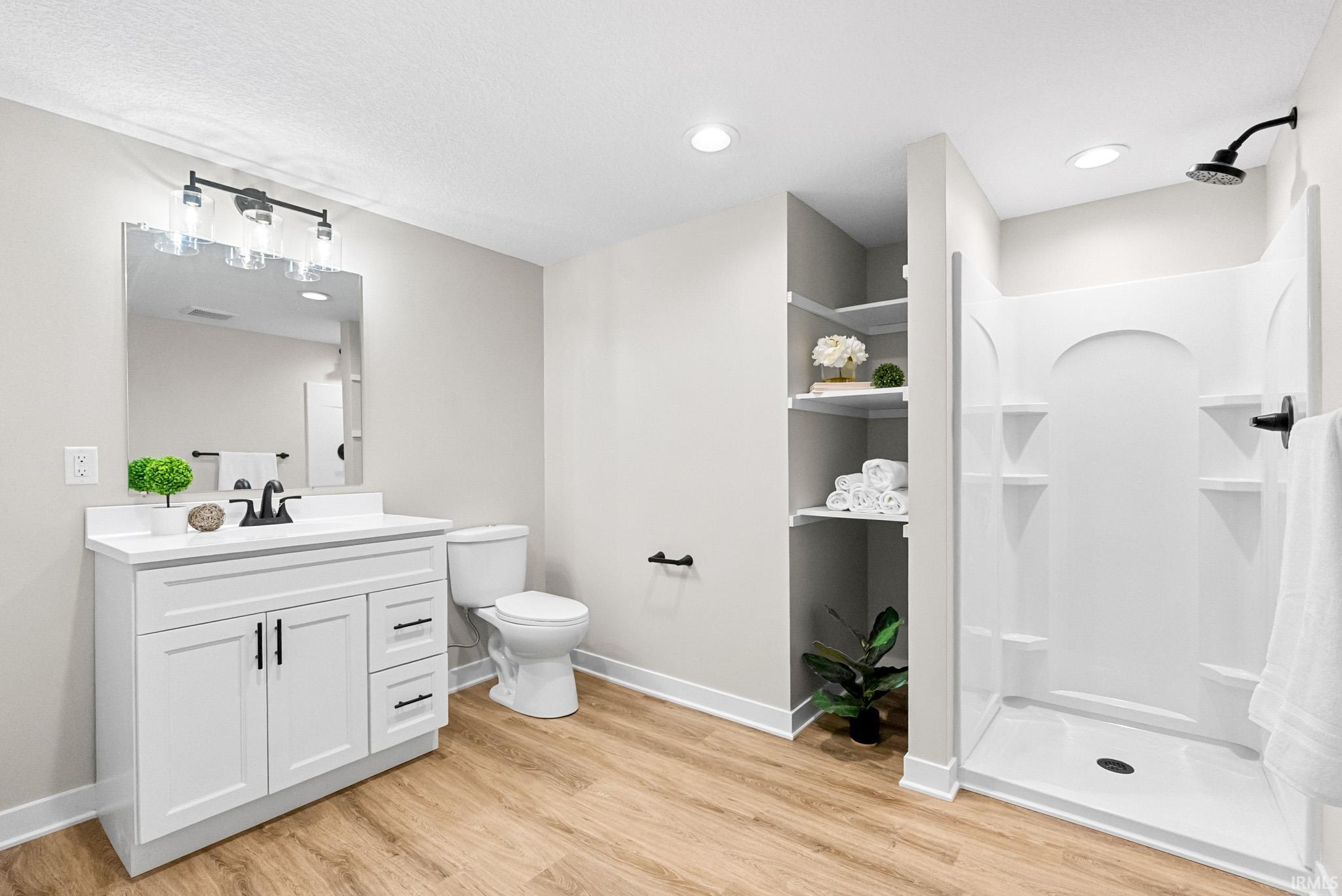 Full bath with a shower stall, vanity, light wood-type flooring, and recessed lighting