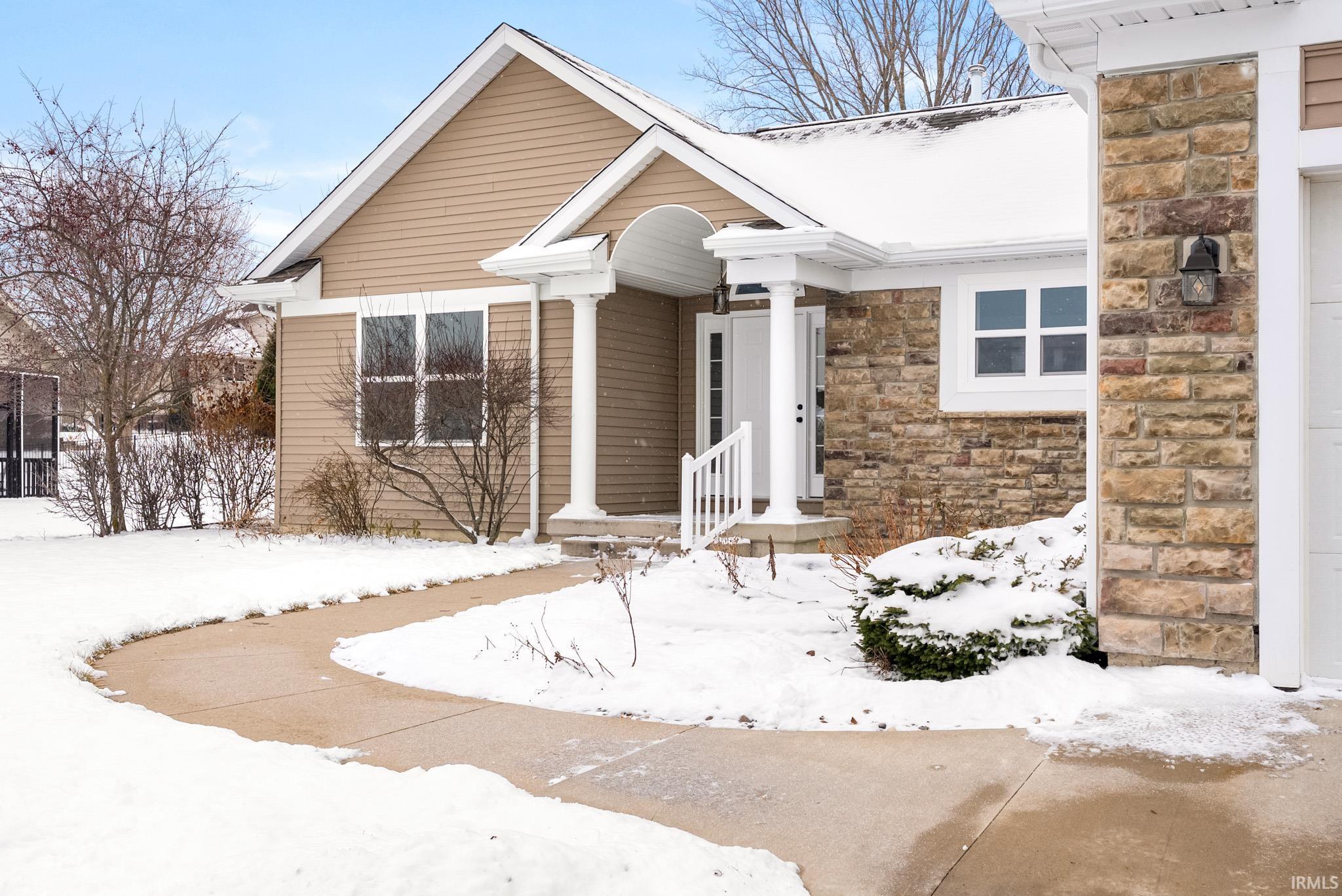 Snow covered property entrance with stone siding