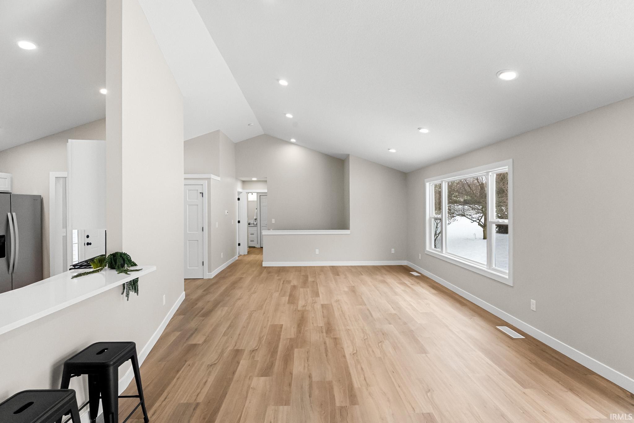 Unfurnished living room with light wood-style flooring, vaulted ceiling, and recessed lighting