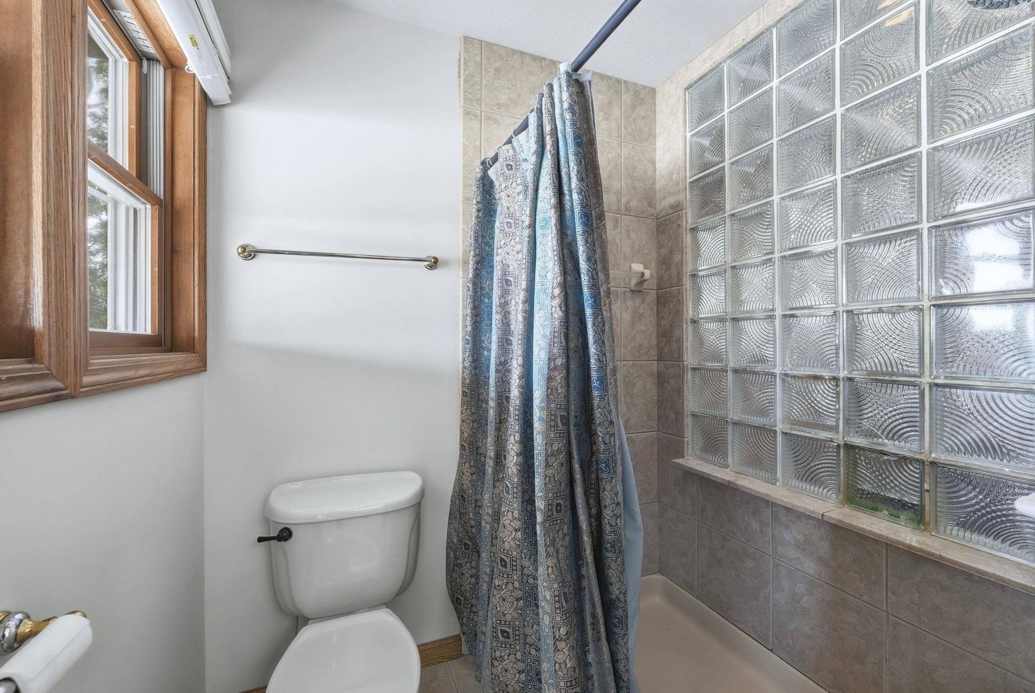 Full bath featuring tiled shower and toilet