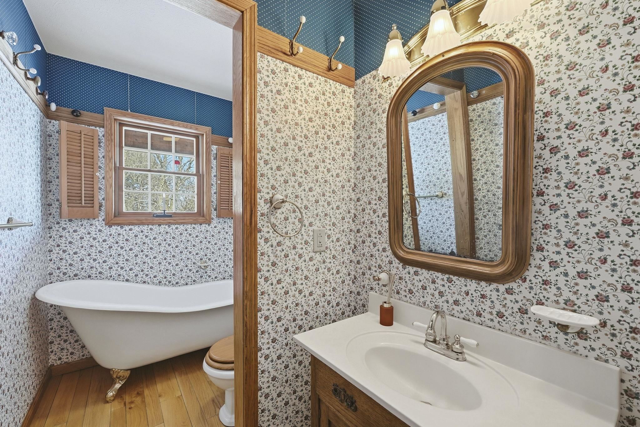 Full bath featuring wallpapered walls, vanity, hardwood / wood-style floors, and a freestanding tub