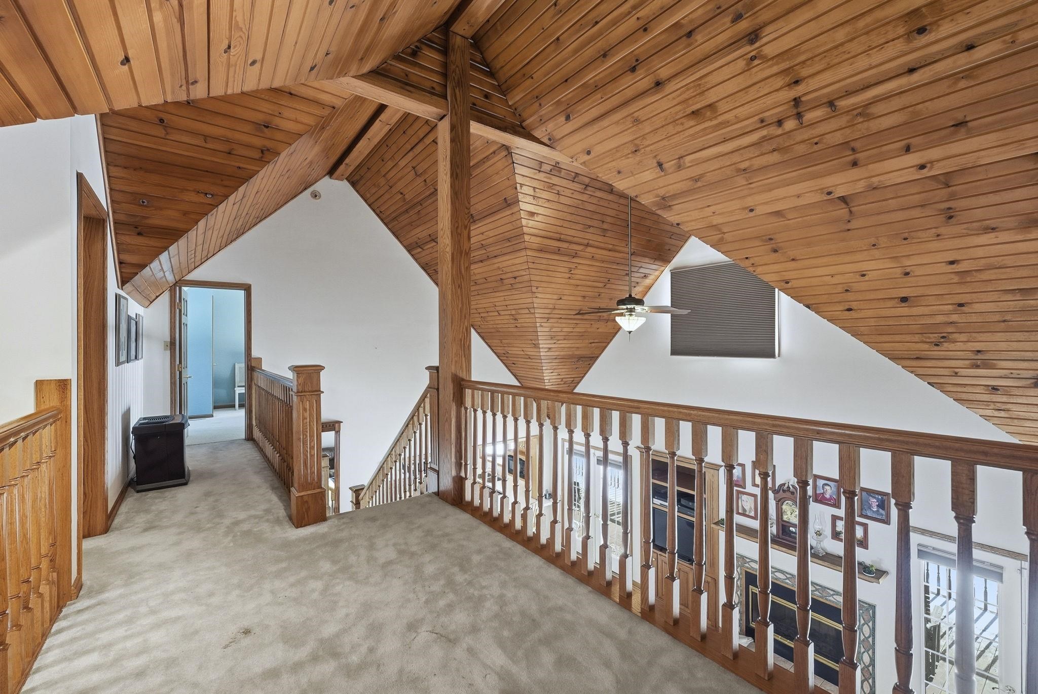 Hallway featuring wooden ceiling, carpet floors, an upstairs landing, and vaulted ceiling