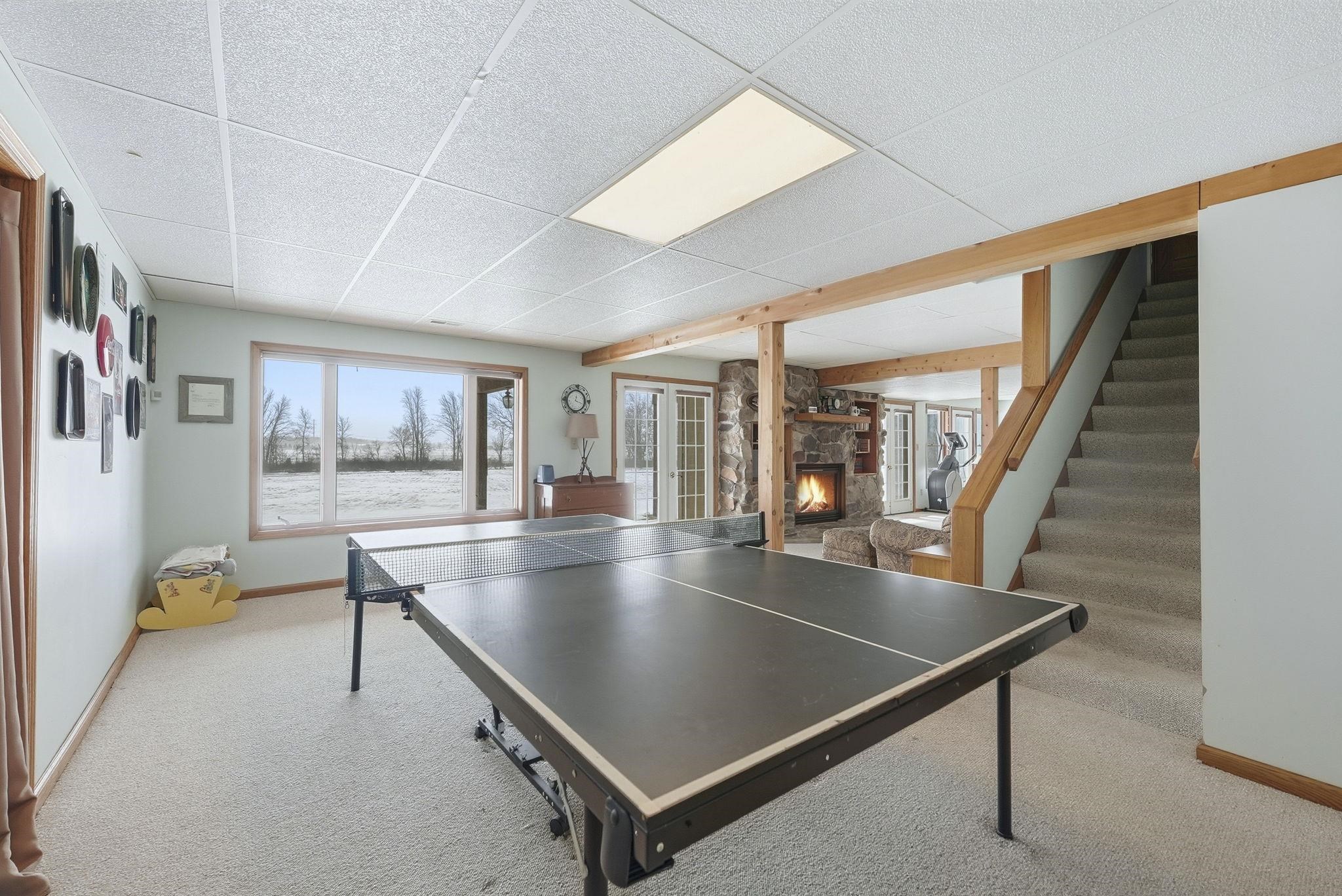 Rec room featuring a fireplace, light carpet, and a drop ceiling