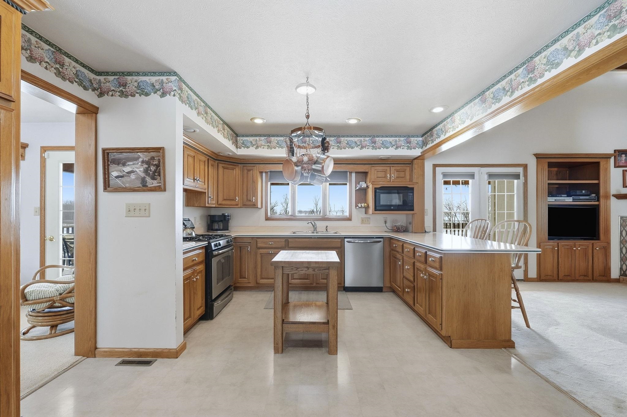 Kitchen with a peninsula, brown cabinetry, a kitchen breakfast bar, stainless steel appliances, and light countertops