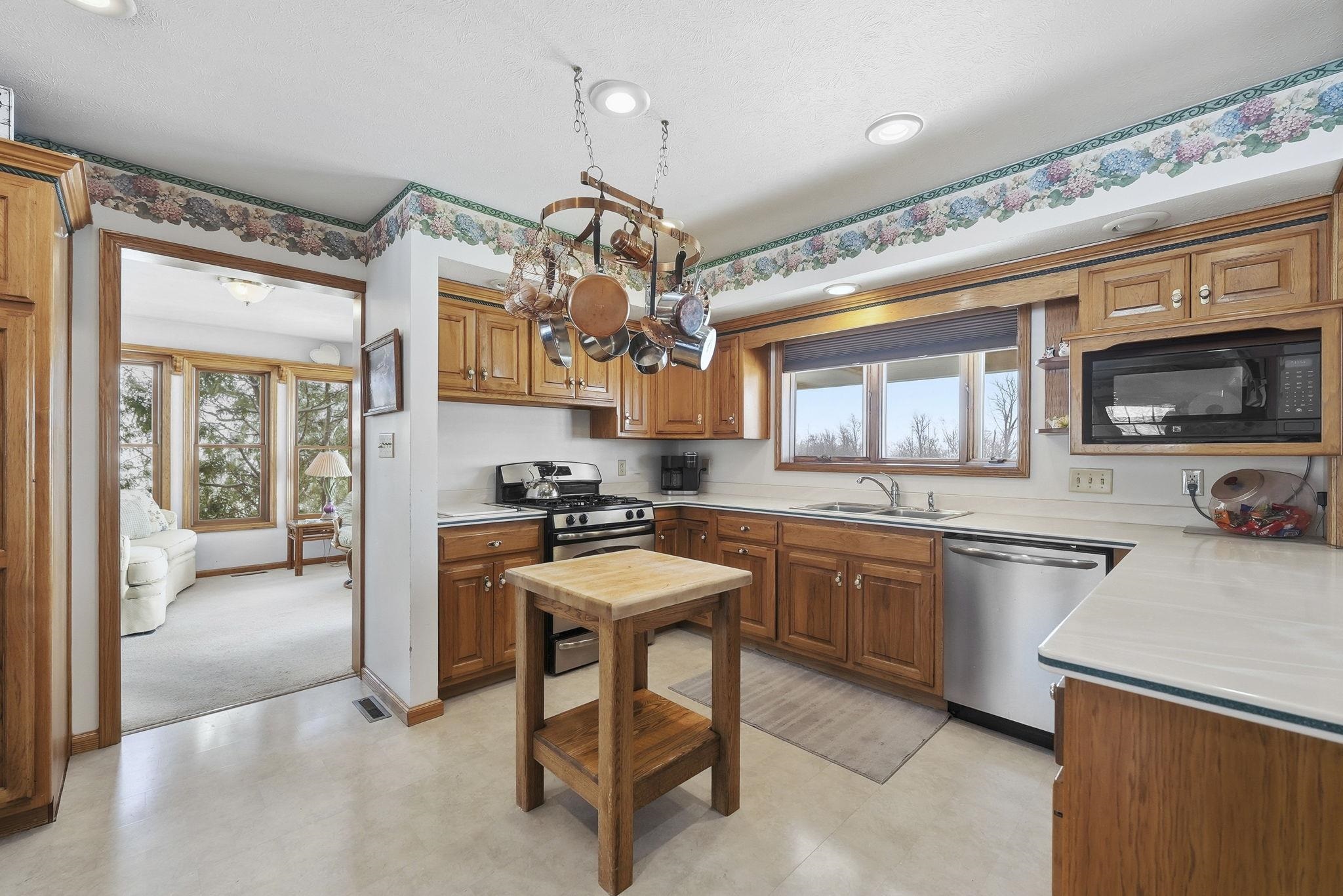 Kitchen featuring light countertops, brown cabinets, appliances with stainless steel finishes, light floors, and recessed lighting