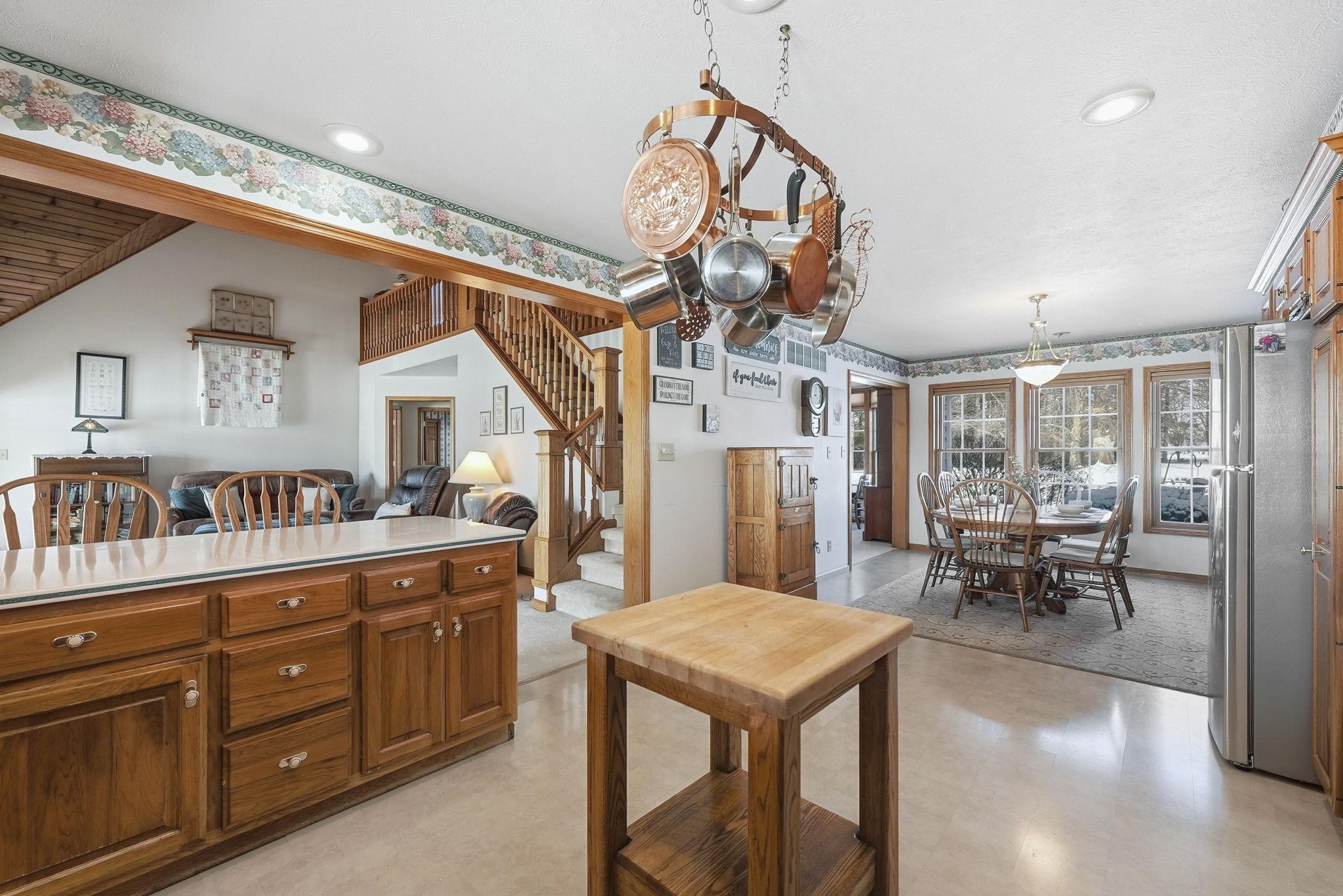 Kitchen featuring light flooring, freestanding refrigerator, open floor plan, and brown cabinets
