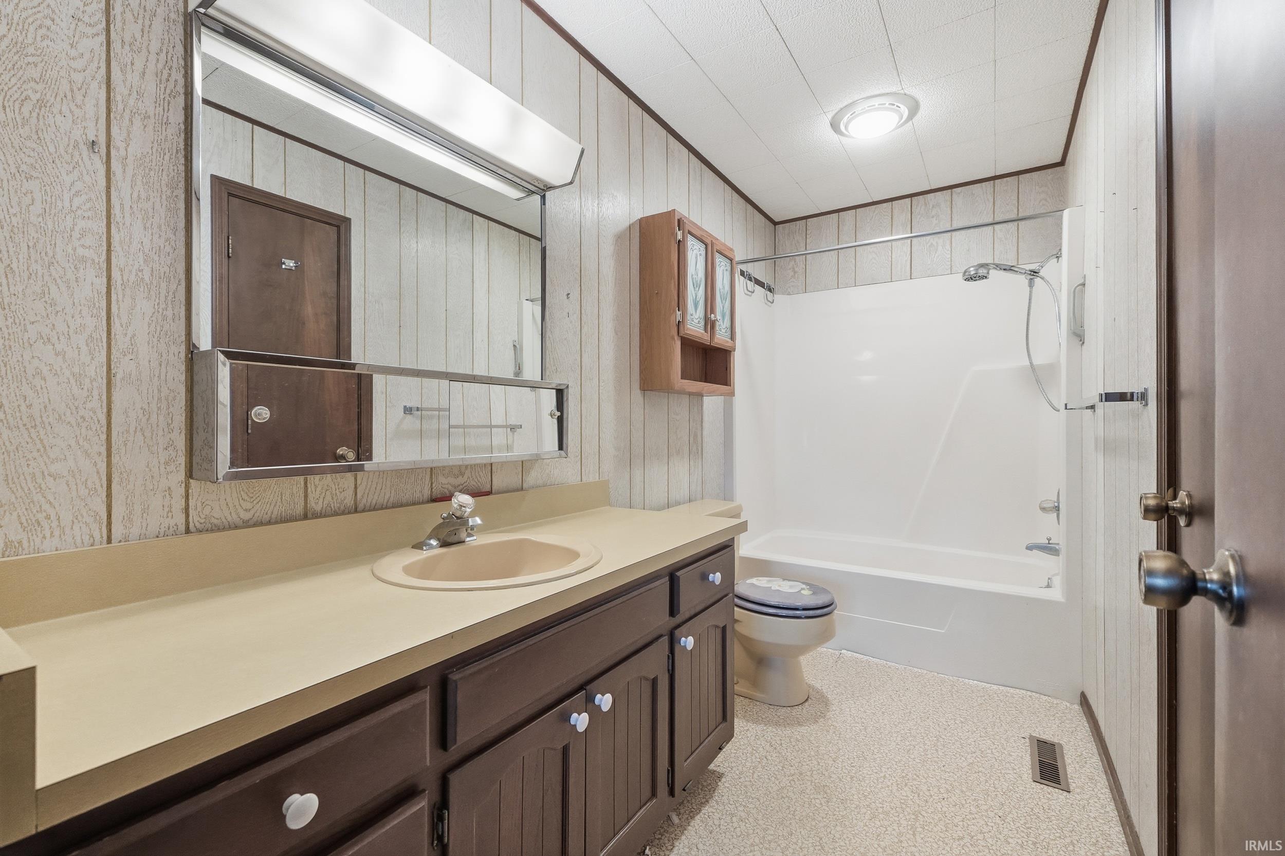 Bathroom with vanity, shower / tub combo with curtain, and wooden walls