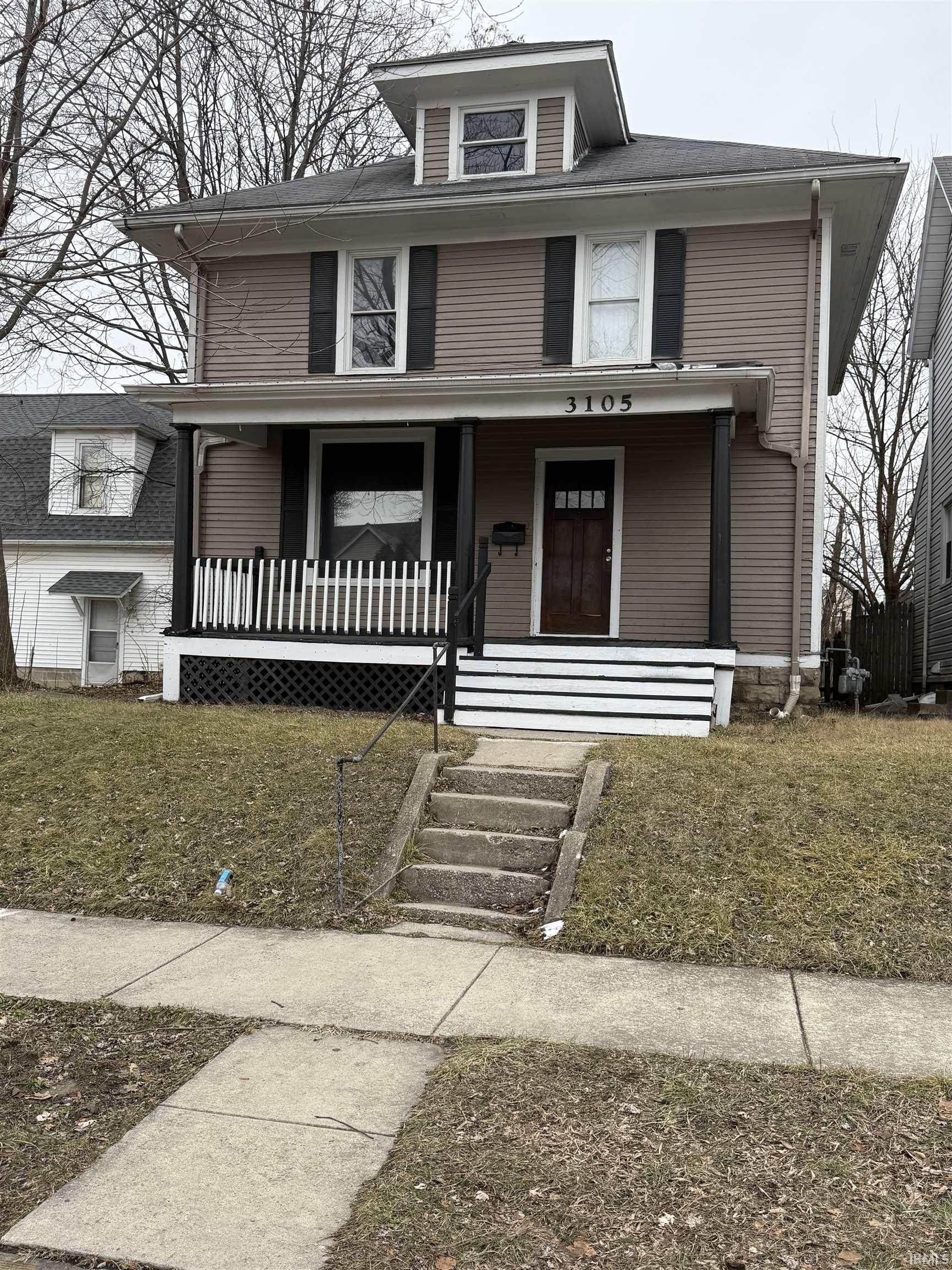 American foursquare style home featuring a porch and a front lawn