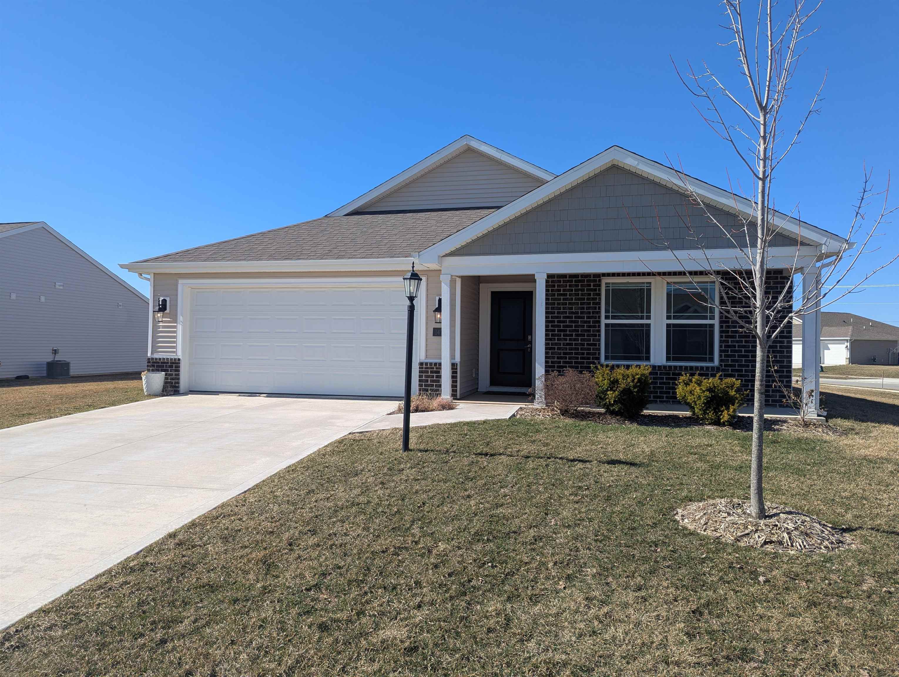 Single story home with concrete driveway, a garage, a front yard, and brick siding