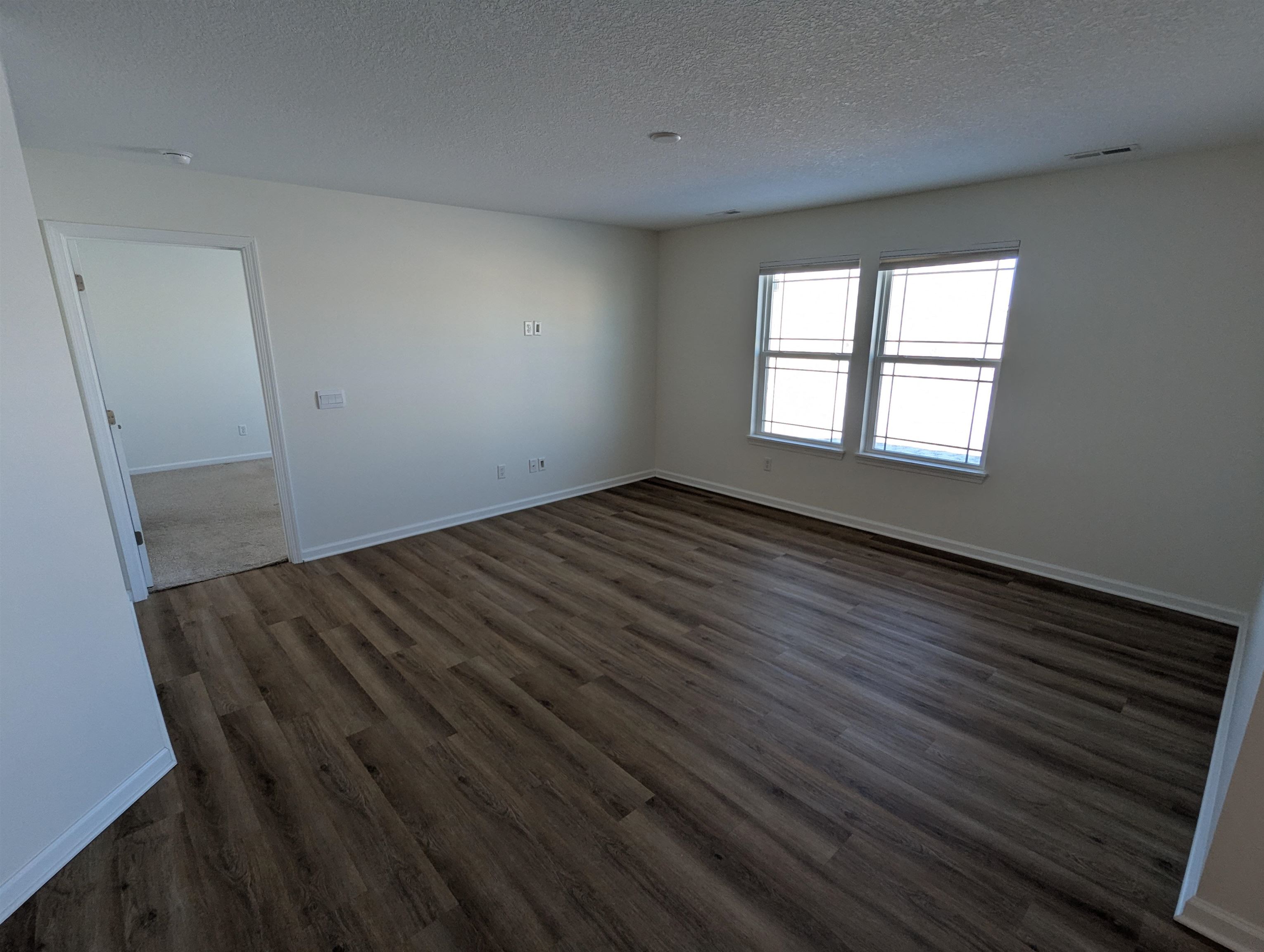 Spare room with a textured ceiling and dark wood-style floors