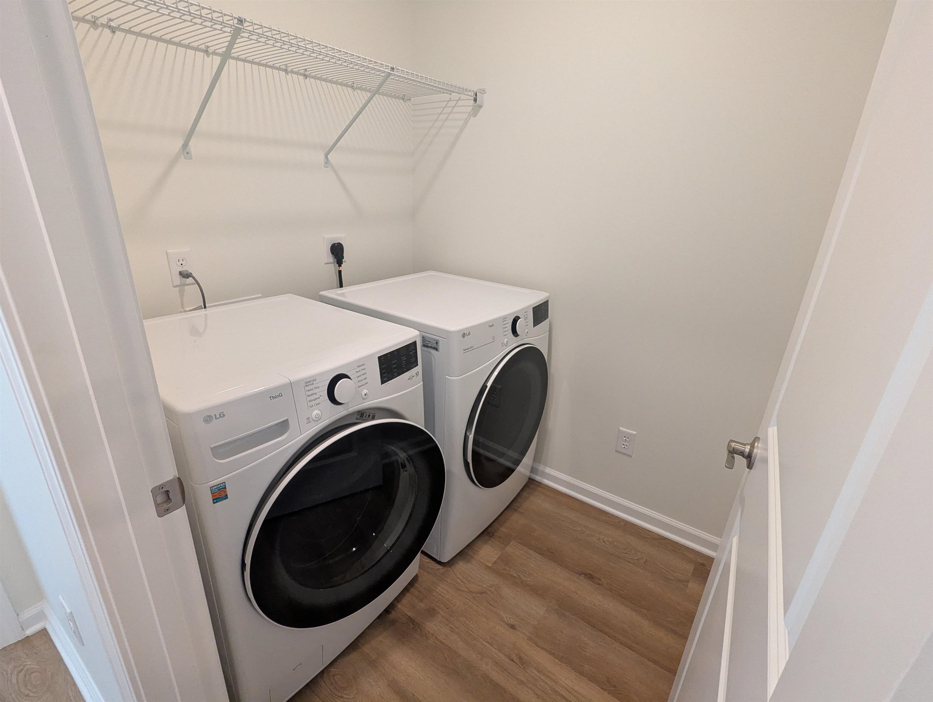 Washroom with wood finished floors and washer and clothes dryer