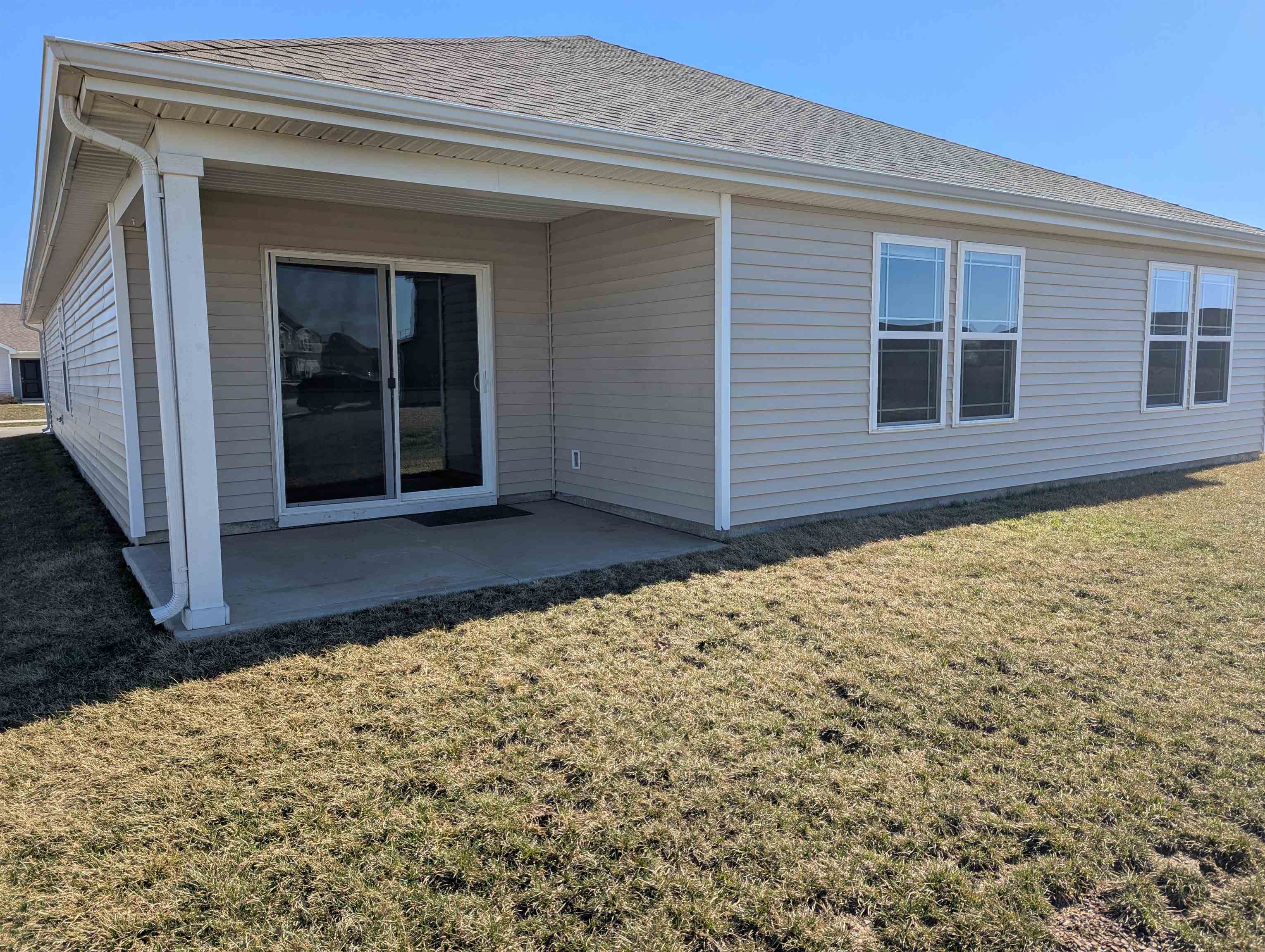 Rear view of house with a lawn, a patio area, and roof with shingles