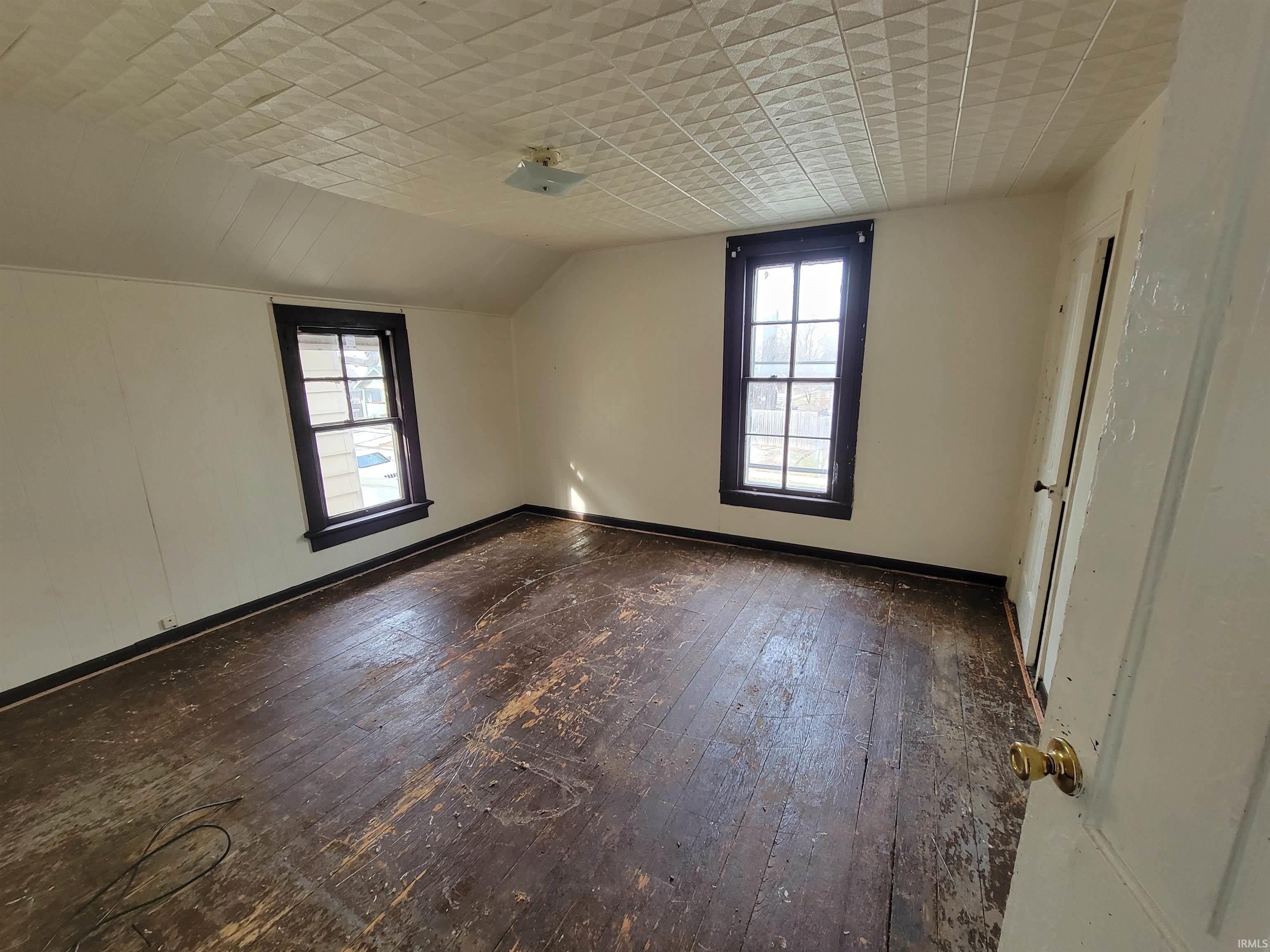 Empty room with lofted ceiling and dark wood-style floors