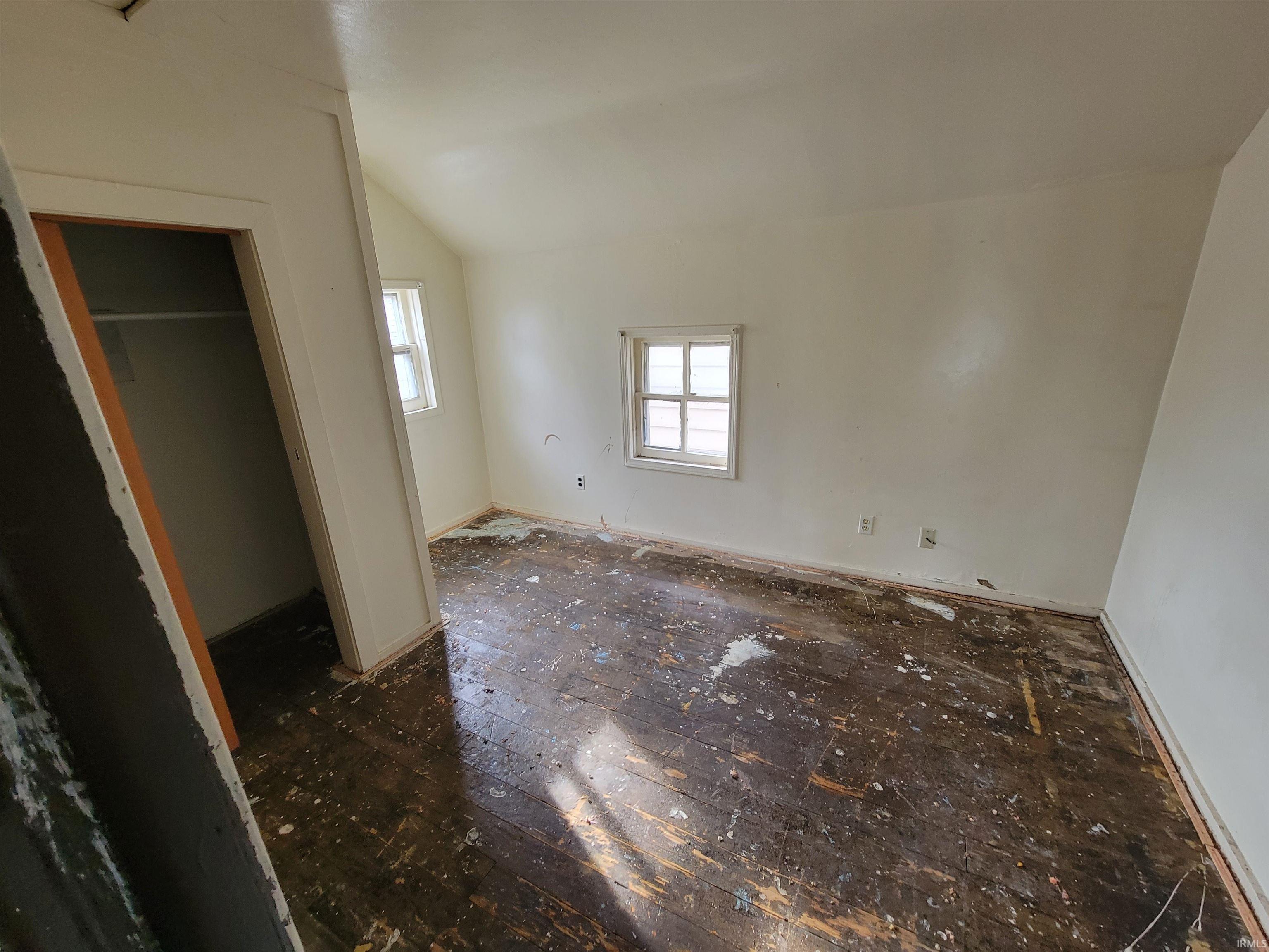 Unfurnished bedroom featuring vaulted ceiling and baseboards
