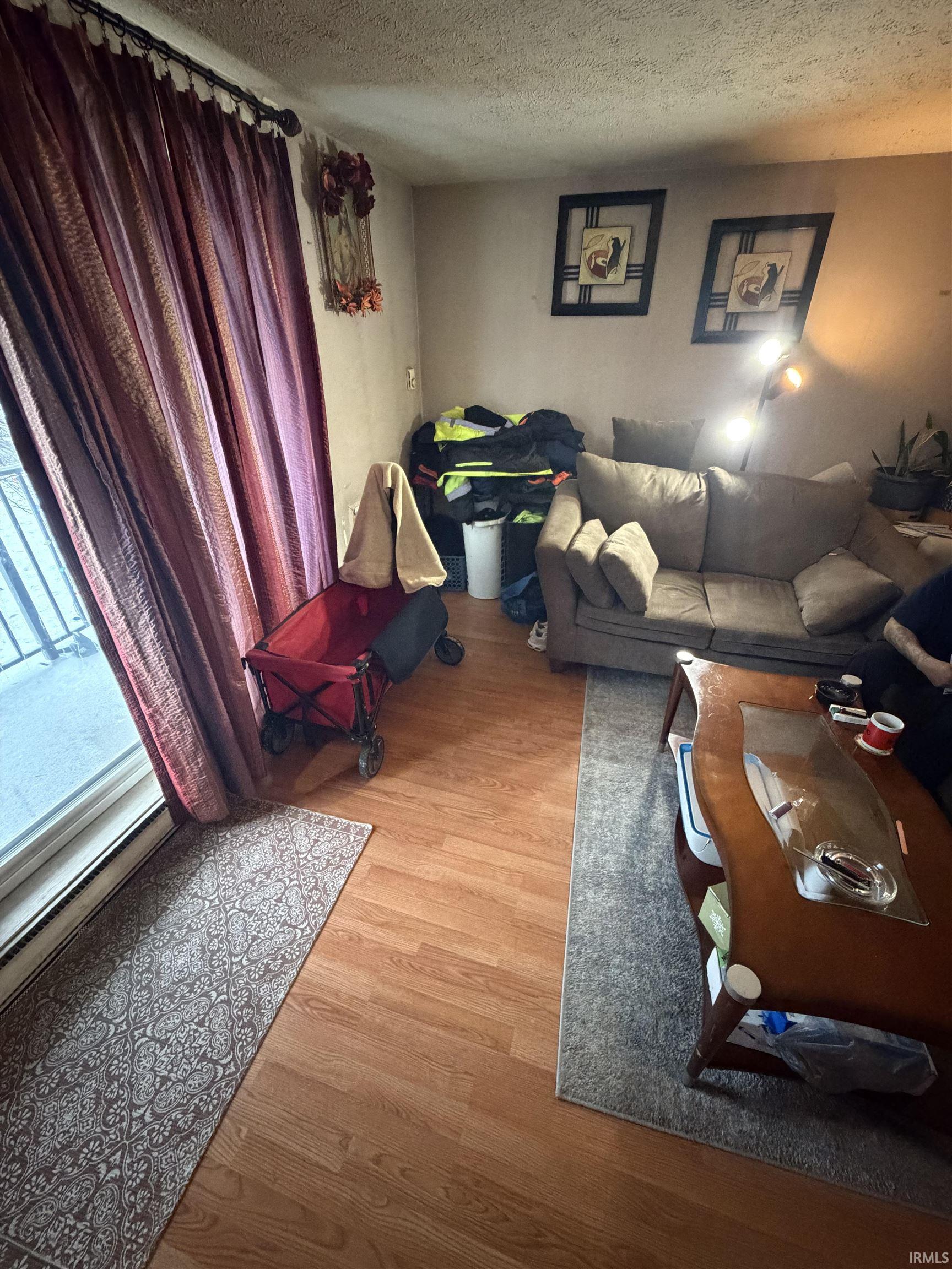 Living area featuring light wood finished floors and a textured ceiling
