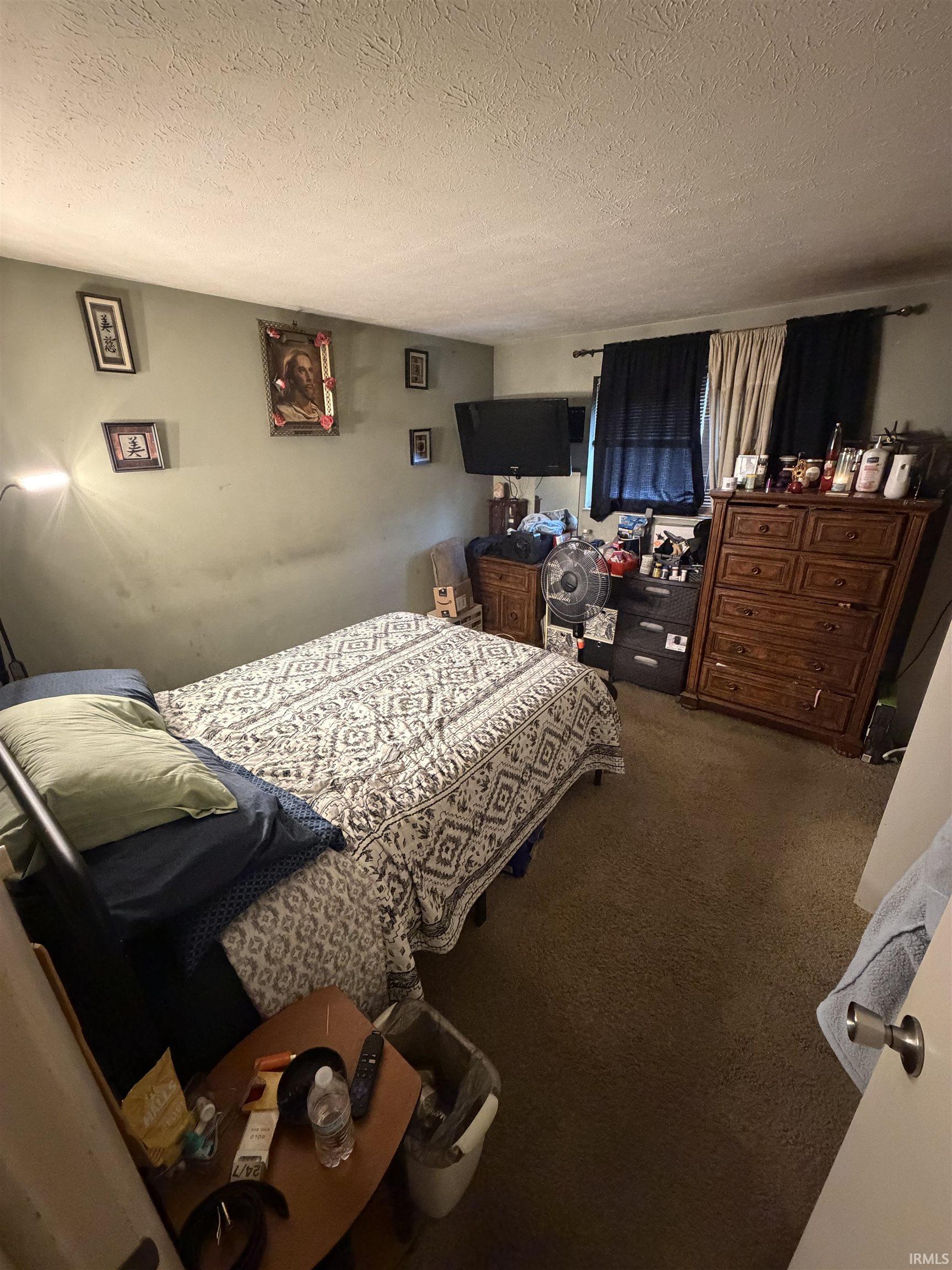 Bedroom with a textured ceiling and carpet
