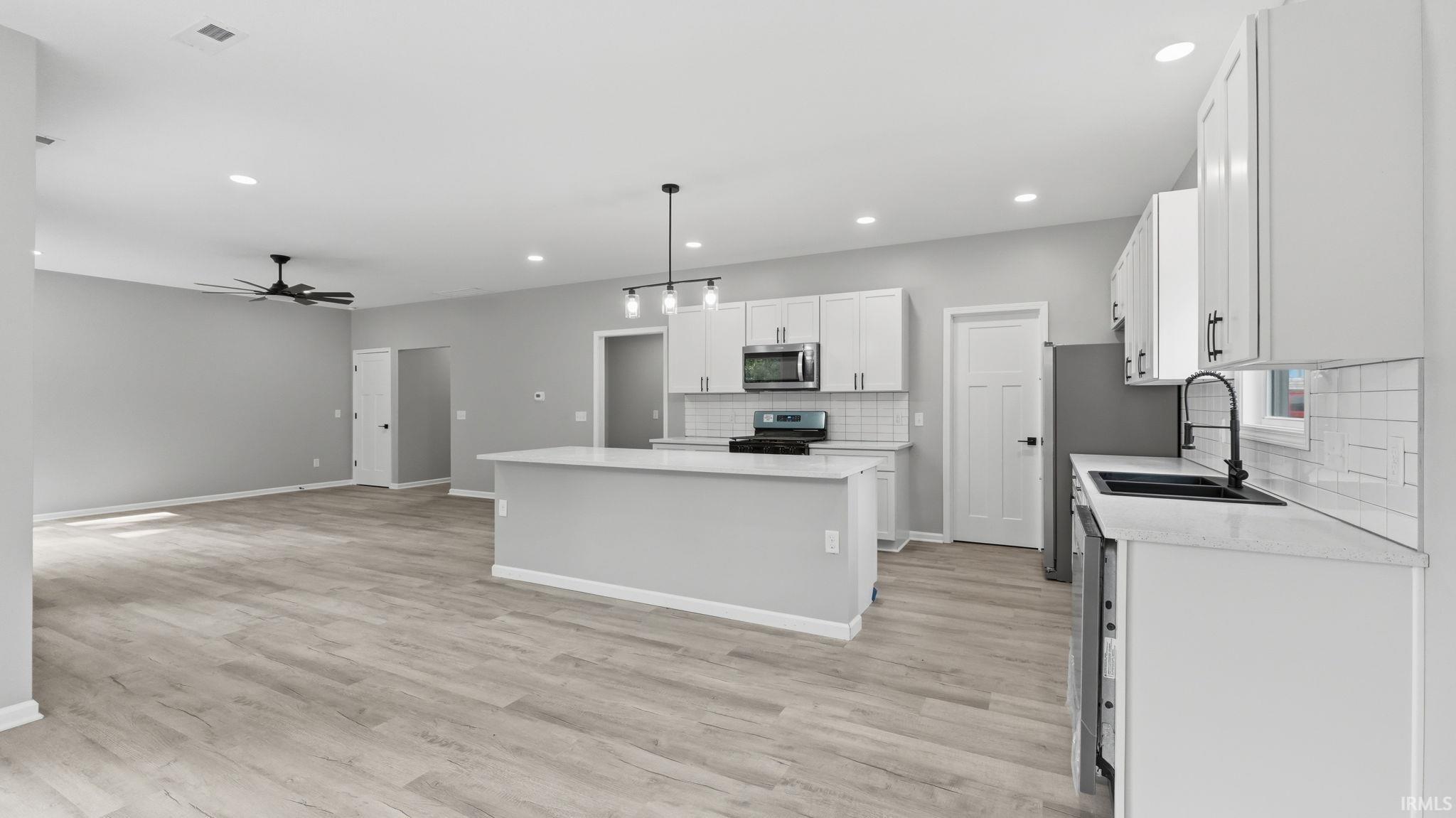 Open-concept living space featuring wood-finish flooring, recessed lighting, and a modern ceiling fan