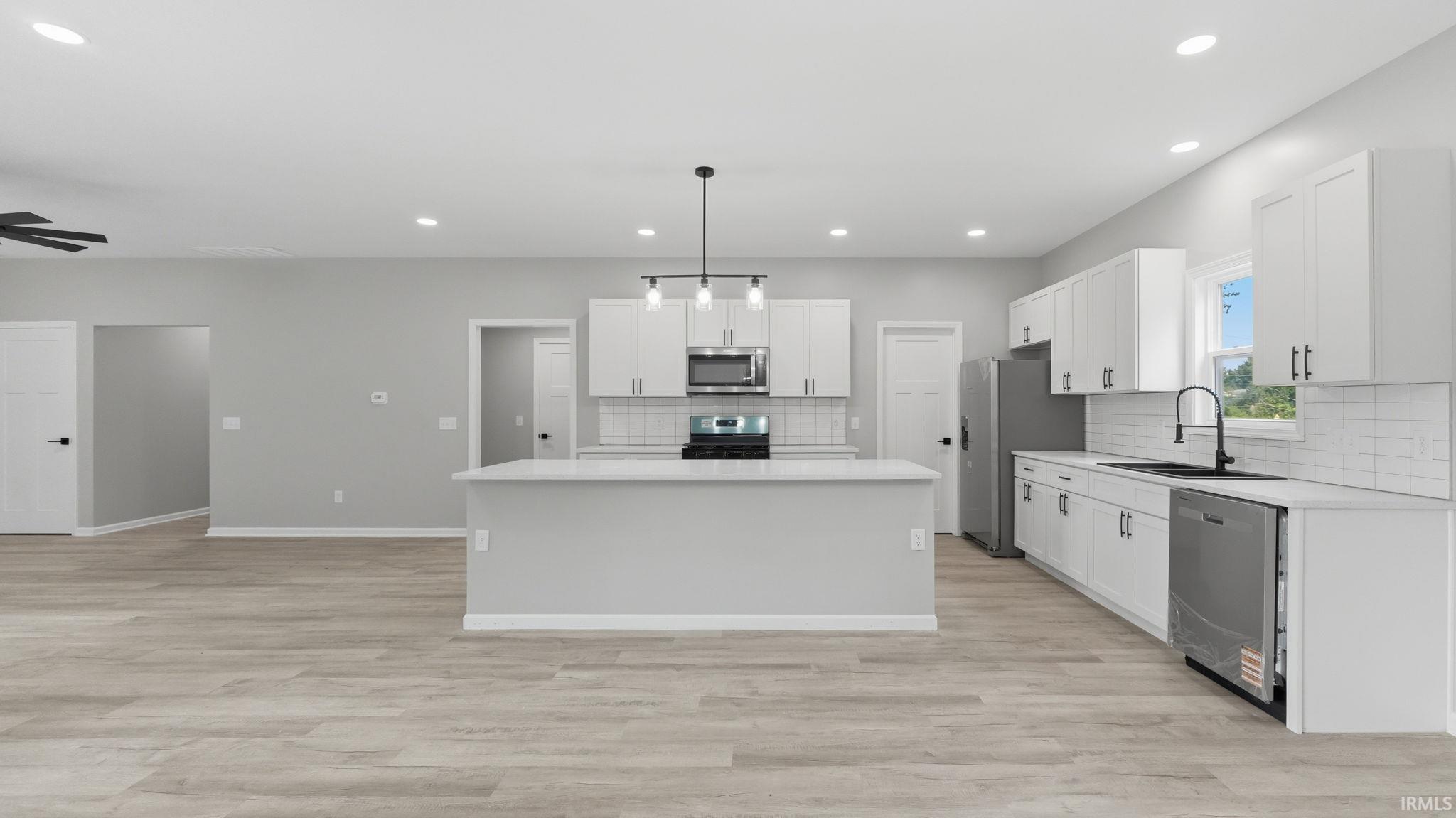 Modern kitchen featuring white cabinetry, light countertops, subway tile backsplash, and stainless steel appliances