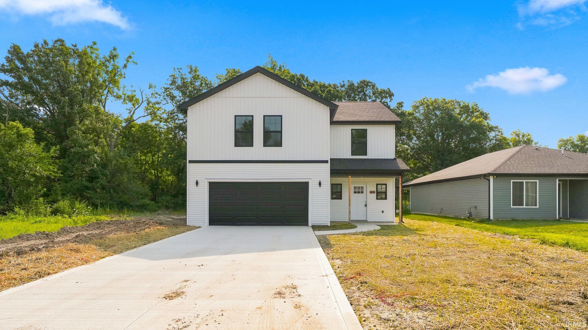 Two-story white exterior with black trim, a prominent garage door, and a concrete driveway