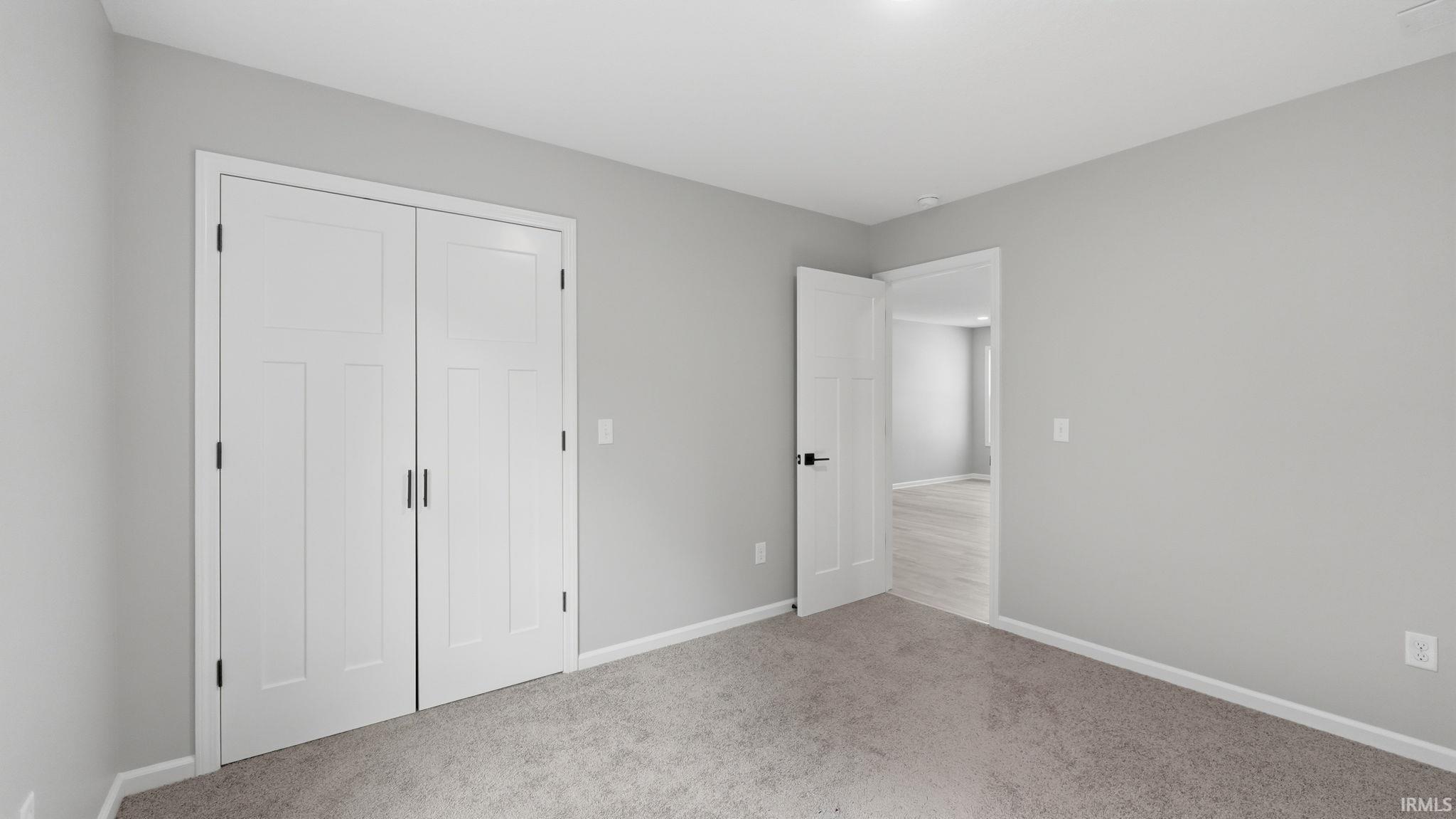 Bedroom featuring neutral gray walls, plush gray carpeting, and white trim