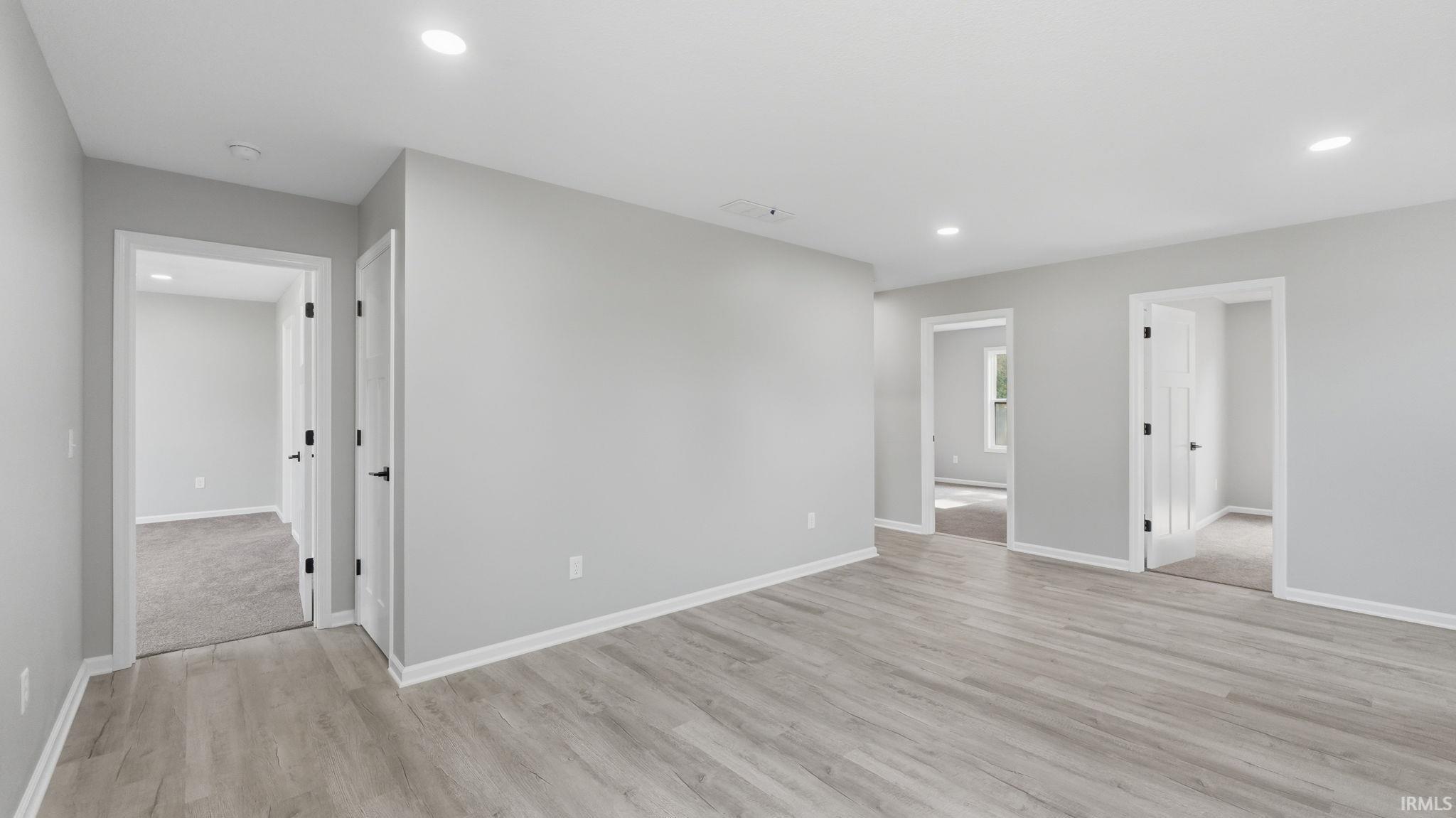 Spacious room featuring wood-finish flooring, light gray wall paint, and white trim