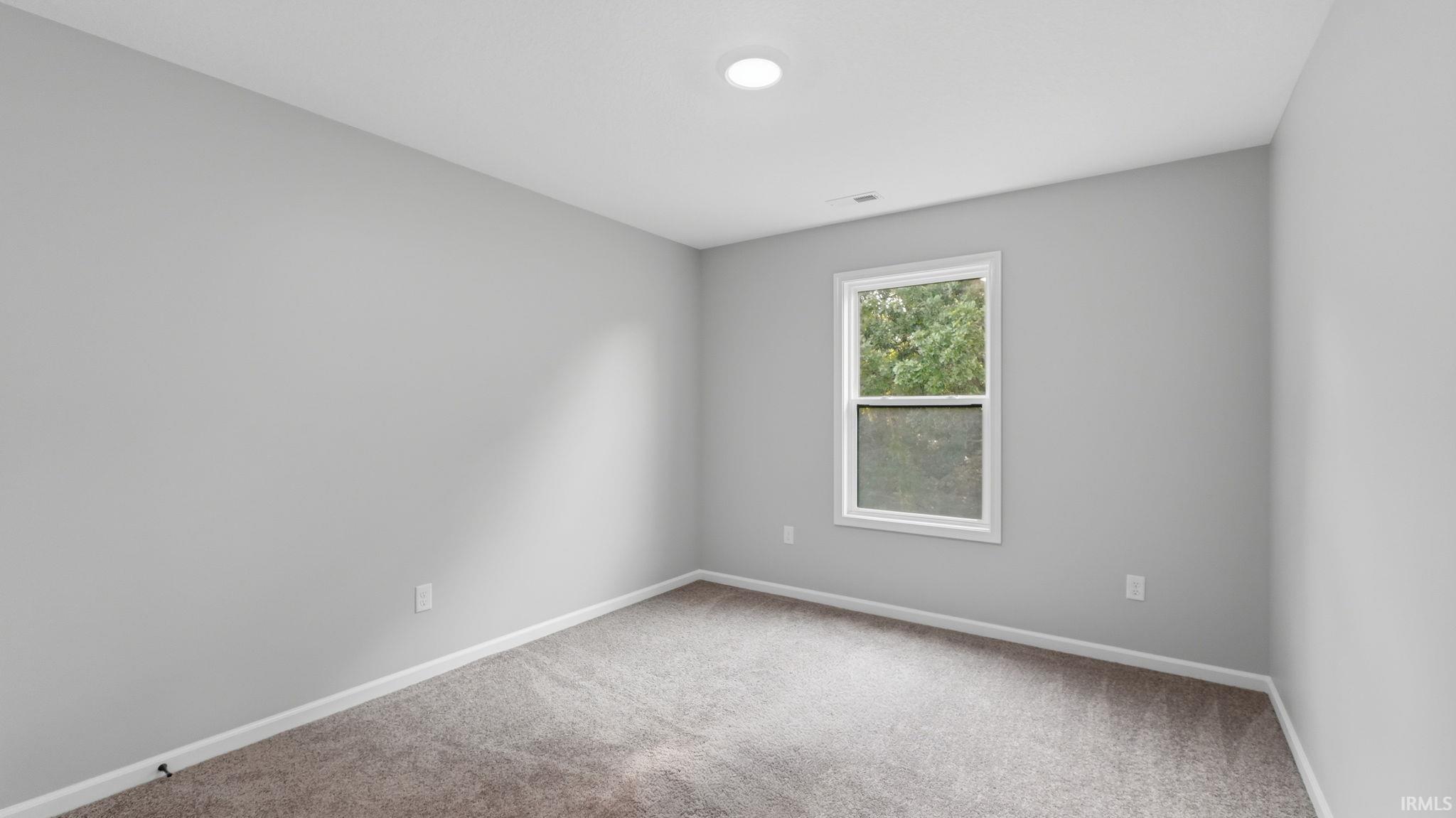 Neutral gray wall paint, white trim, recessed ceiling lighting, and a window with green foliage visible