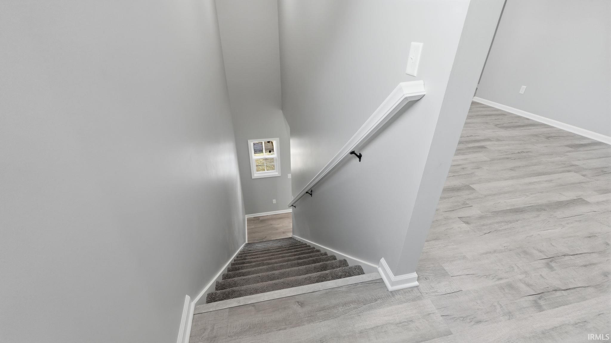 Staircase featuring light gray carpeting, white painted handrail, and white baseboards