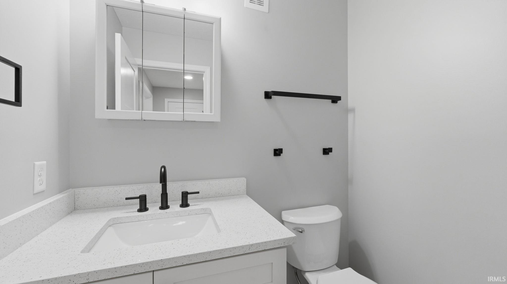 Bathroom featuring a white vanity with a speckled countertop, undermount sink, and matte black faucet