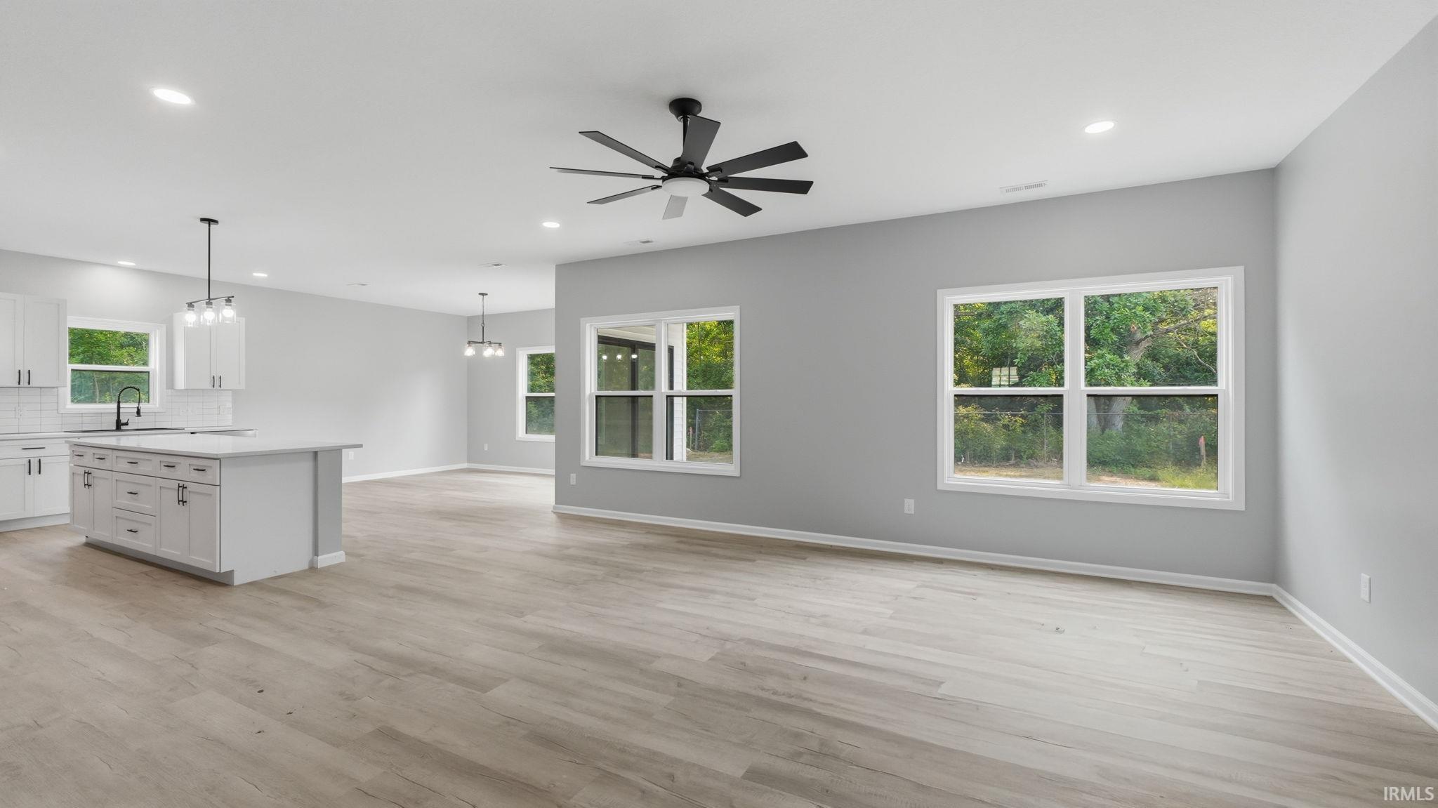 Open-concept living area featuring light wood-finish flooring, recessed lighting, and a contemporary ceiling fan