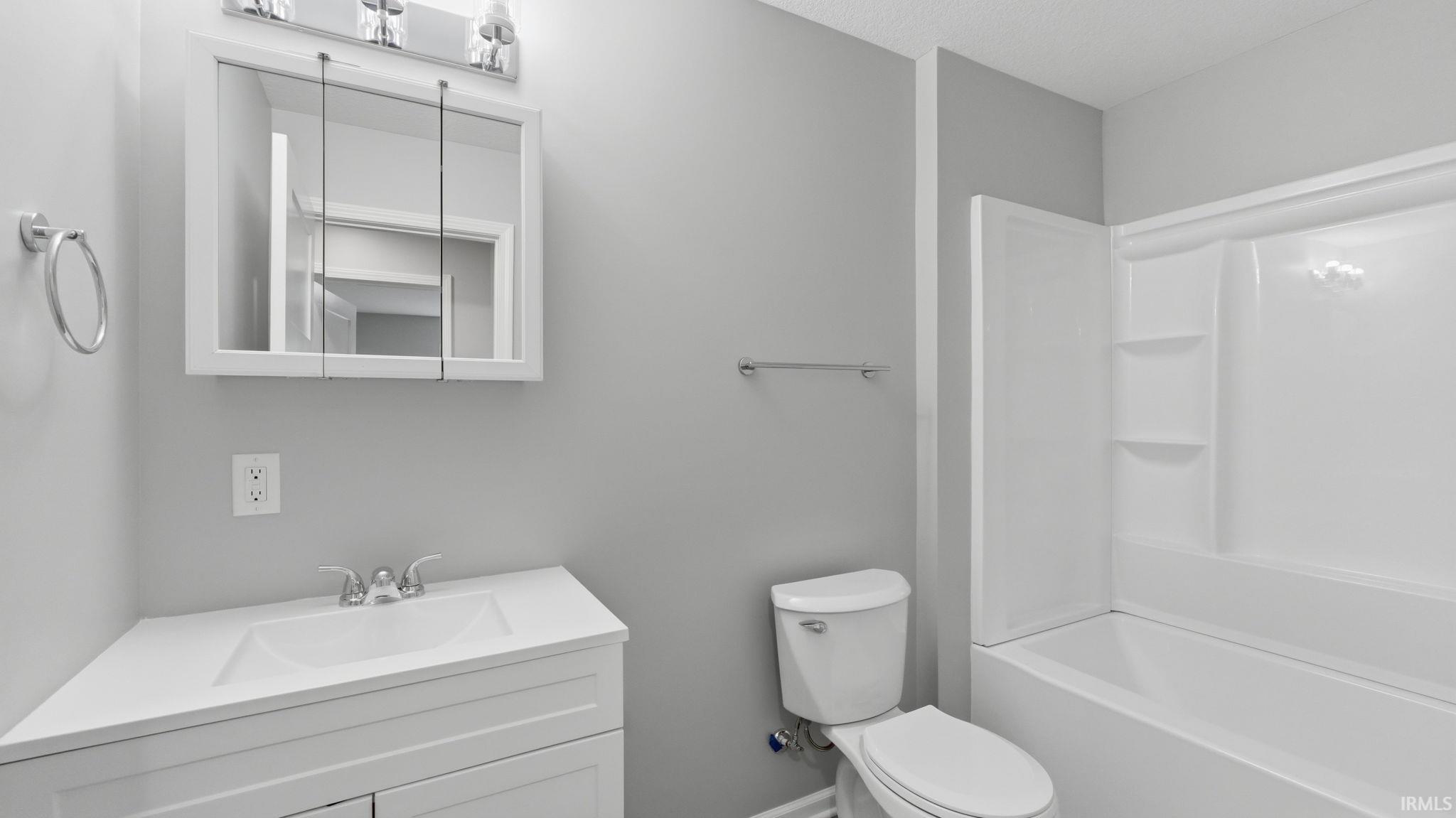 Bathroom featuring a white vanity with integrated sink, chrome faucet, and a wall-mounted medicine cabinet with a light fixture