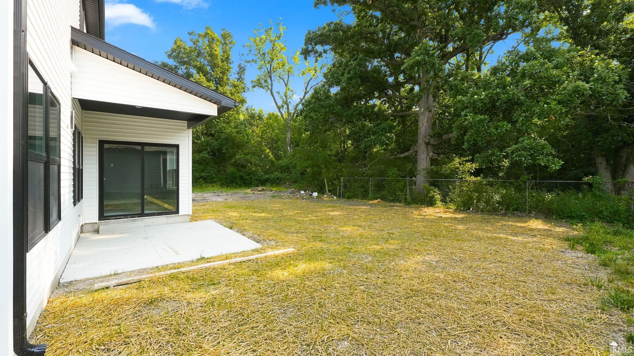 Modern exterior with white siding and black-framed windows, featuring a sliding glass door leading to a concrete patio