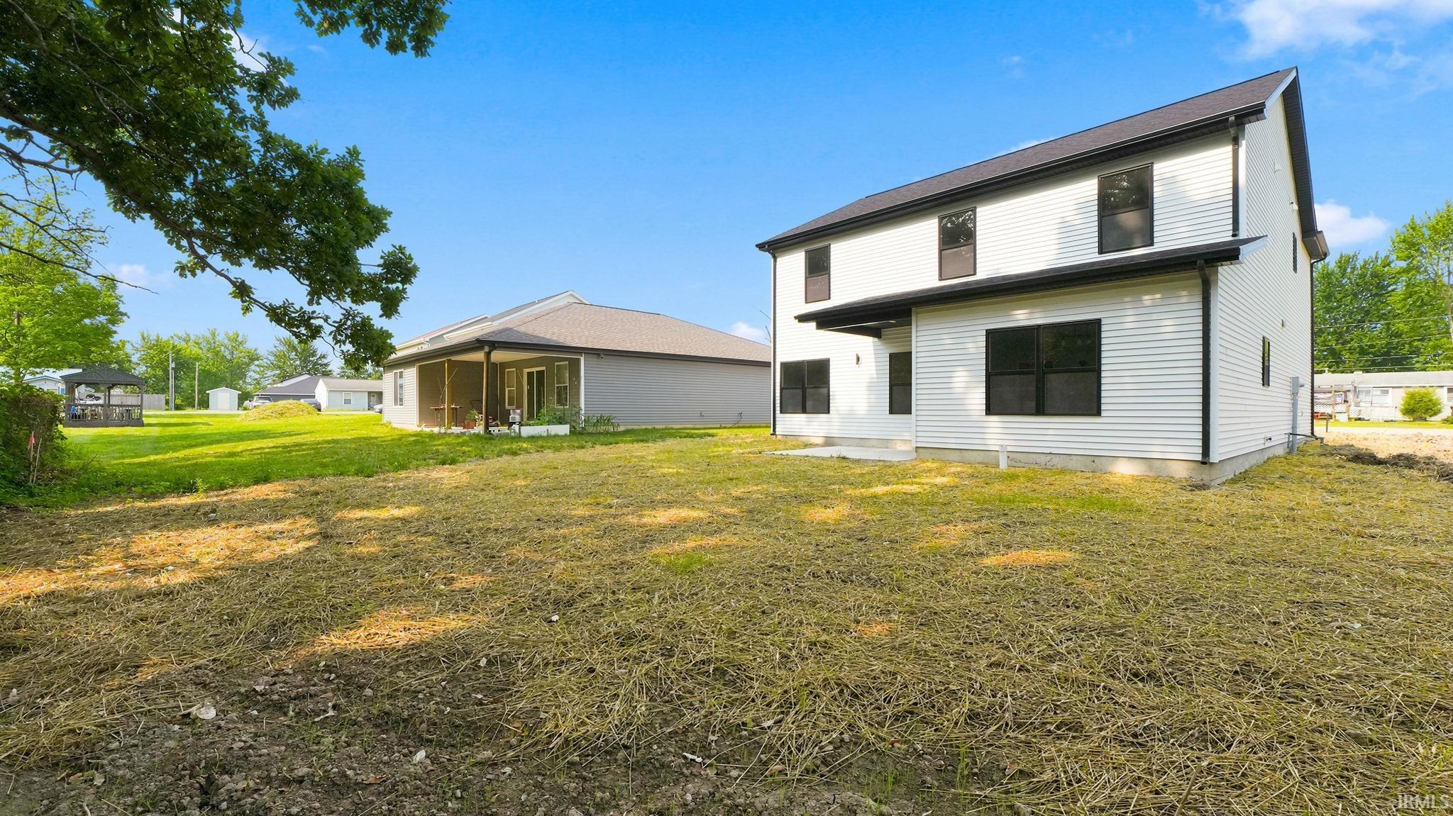 Two-story residence featuring white horizontal siding, dark-framed windows, and a black roof
