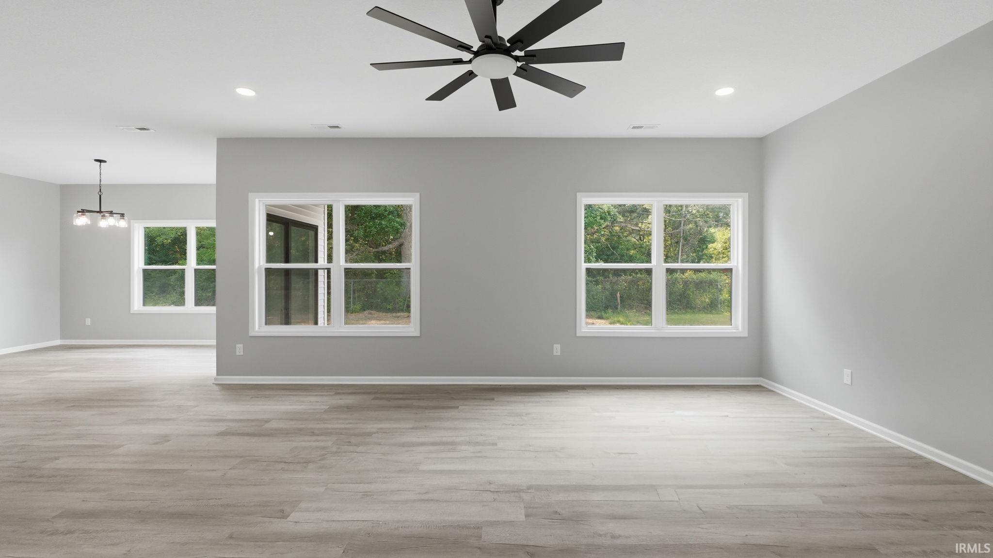 Spacious living area featuring light wood-finish flooring, light gray walls, and recessed lighting