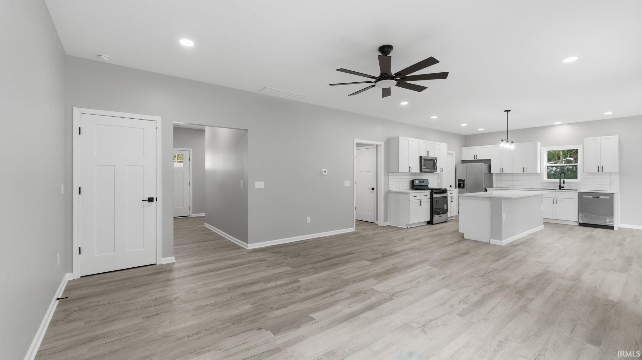 Open-concept living area featuring wood-finish flooring, recessed lighting, and a modern ceiling fan