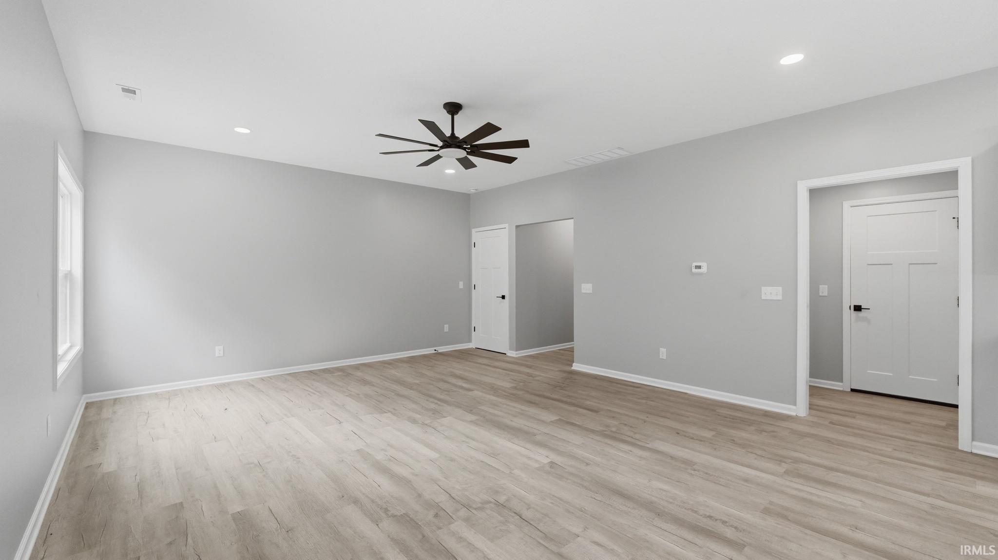 Spacious room featuring light wood-finish flooring, recessed lighting, and a contemporary black ceiling fan